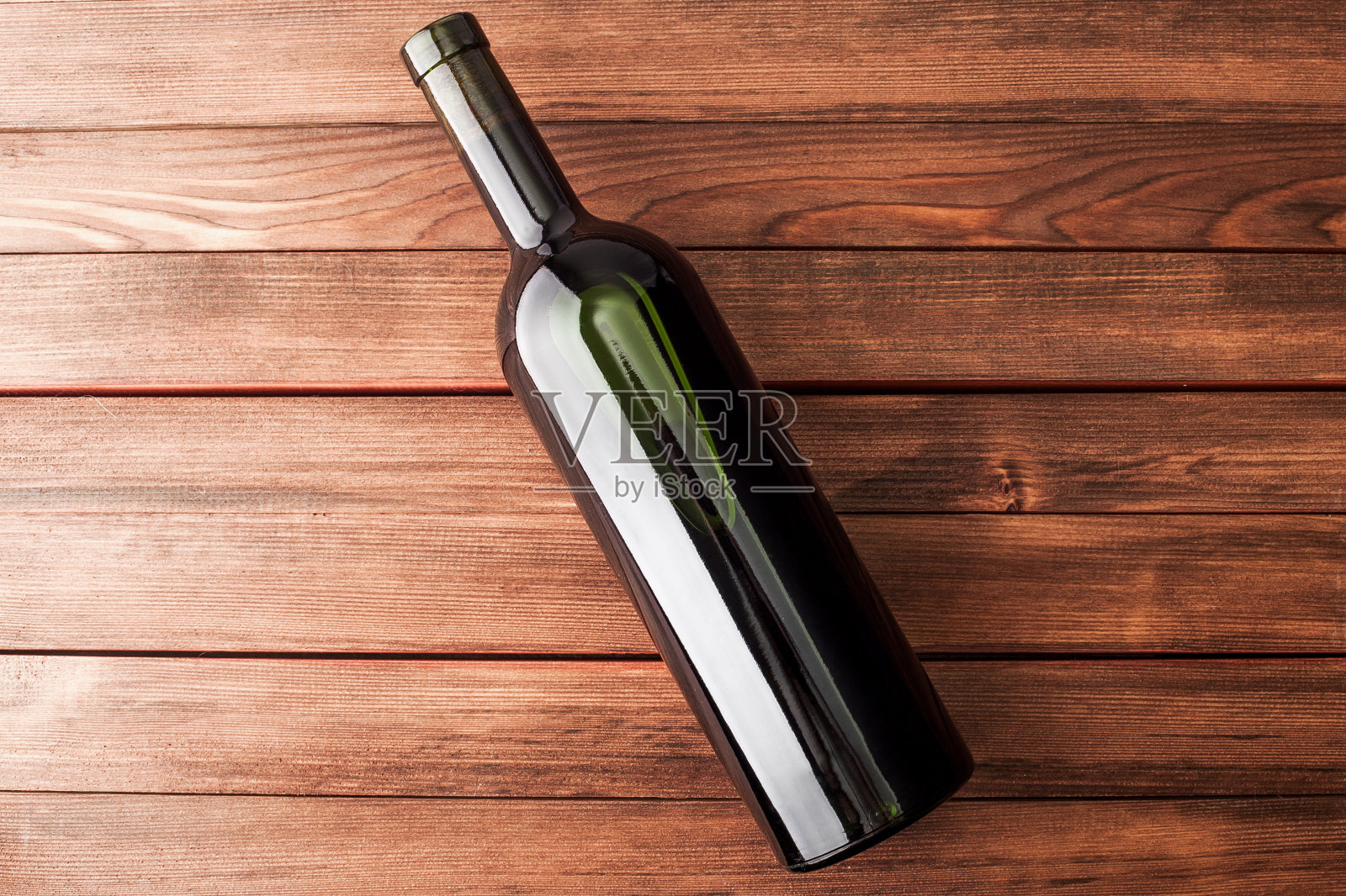 木桌上放着一瓶深色葡萄酒。照片摄影图片