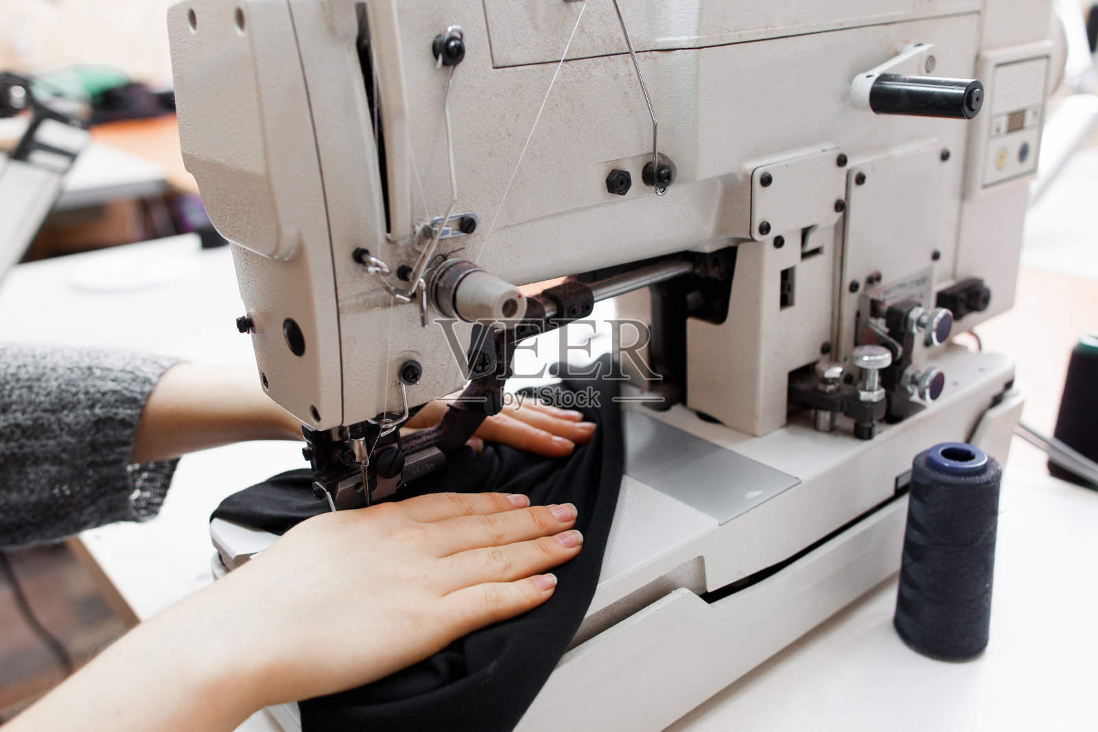 在缝纫机上缝制深色织物的妇女照片摄影图片