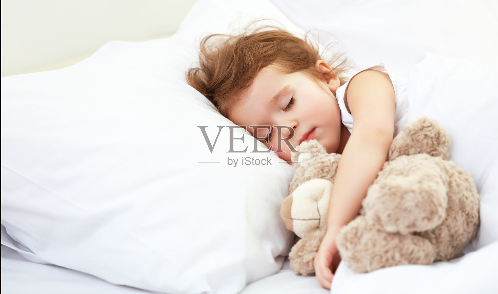 小女孩和泰迪熊睡在床上照片摄影图片