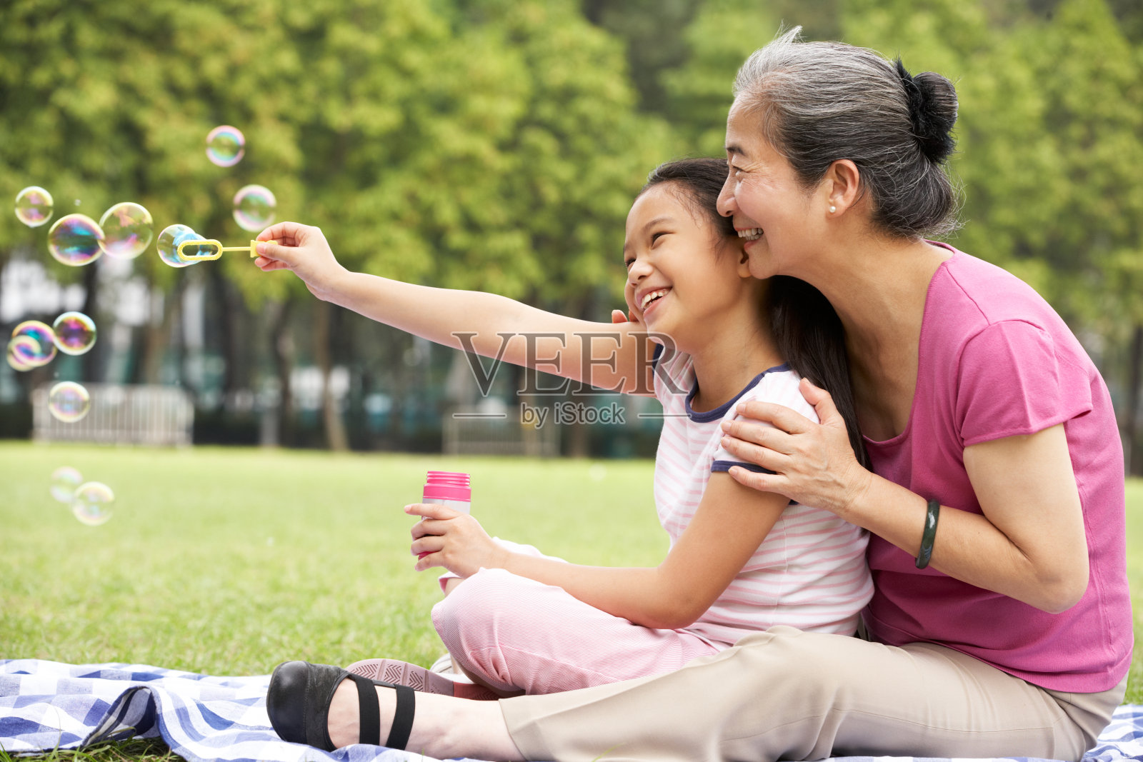 中国奶奶和孙女在公园吹泡泡照片摄影图片
