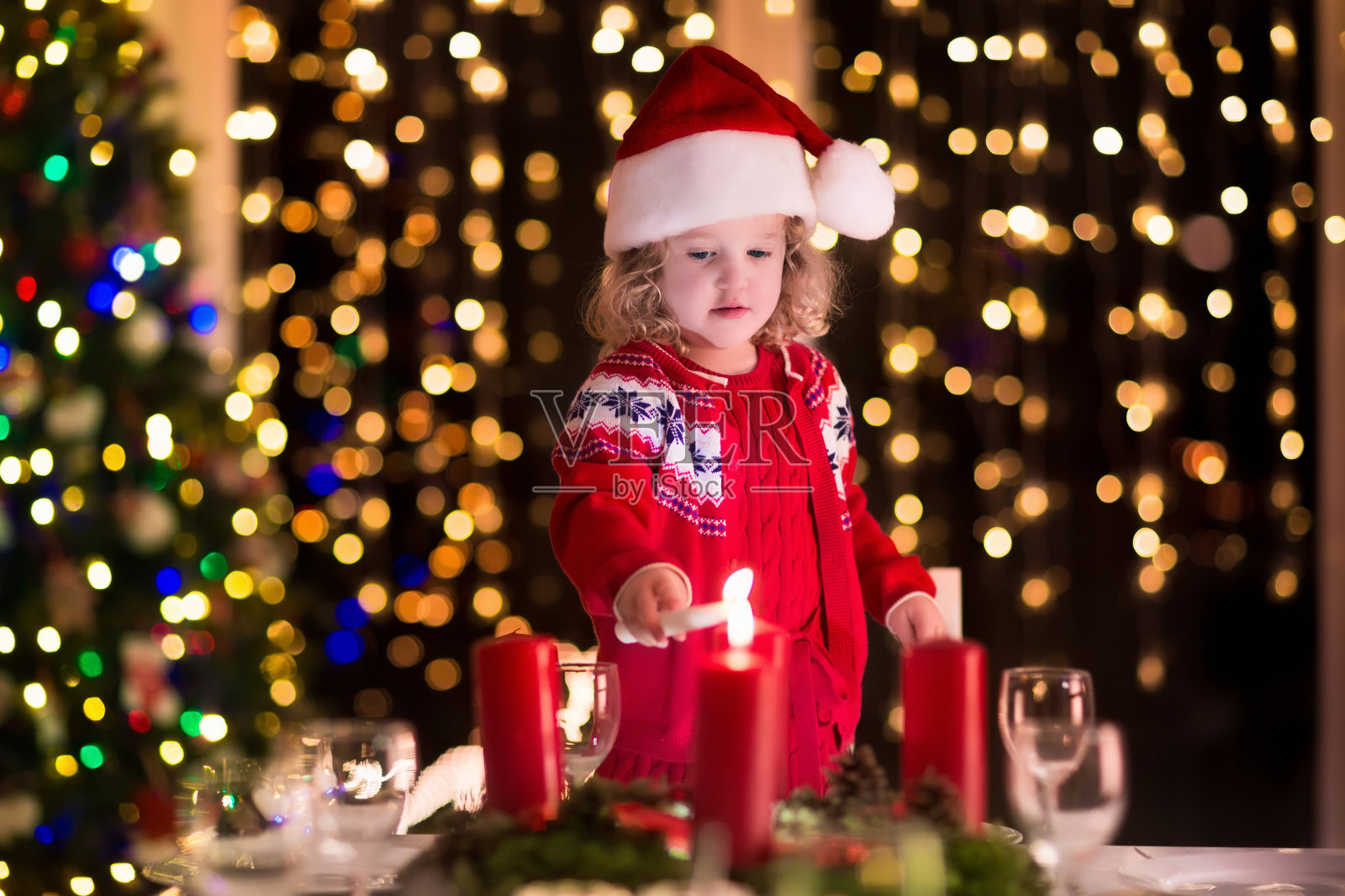 小女孩在圣诞夜的晚餐上点燃蜡烛照片摄影图片