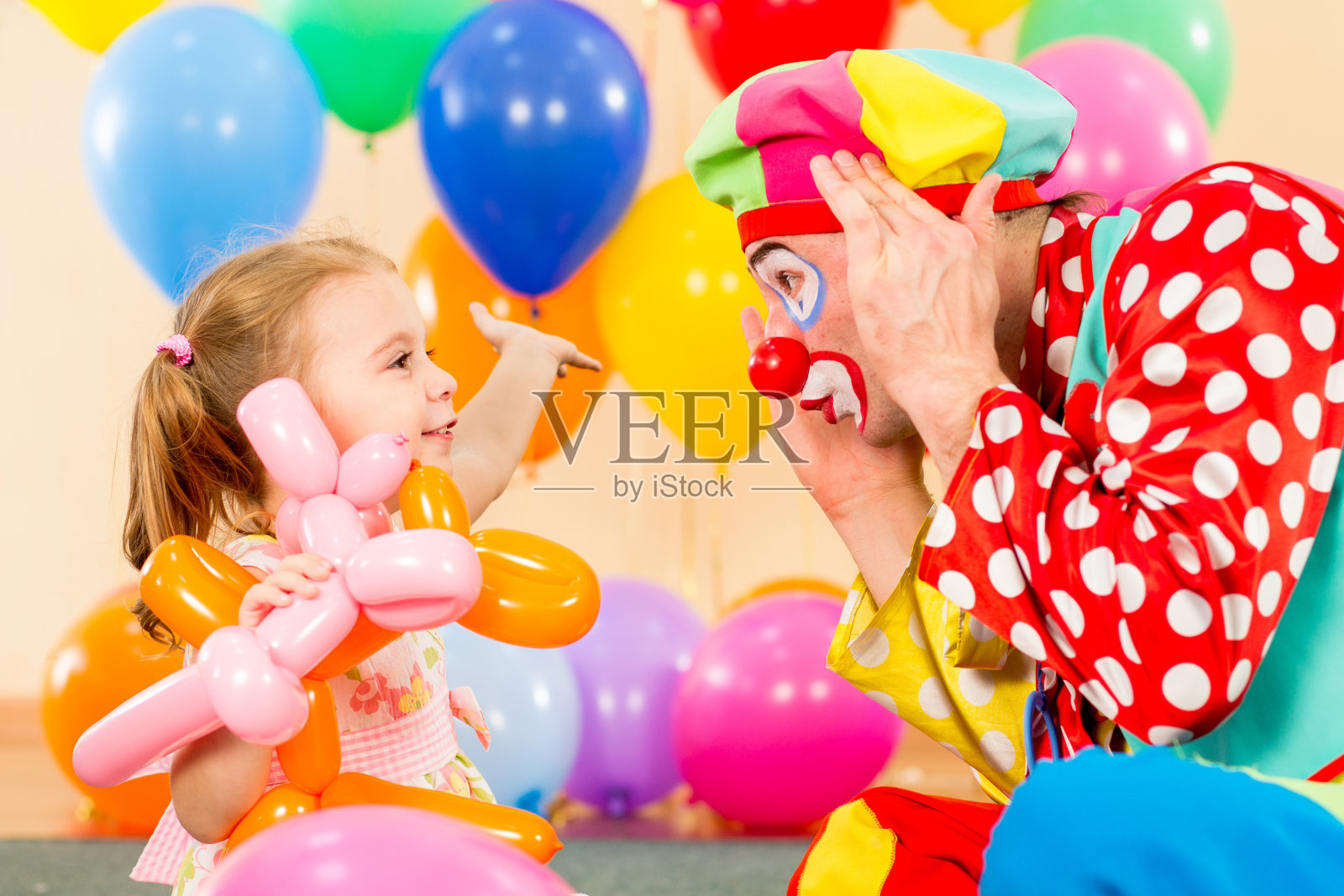 快乐的小女孩和小丑在生日派对上玩耍照片摄影图片