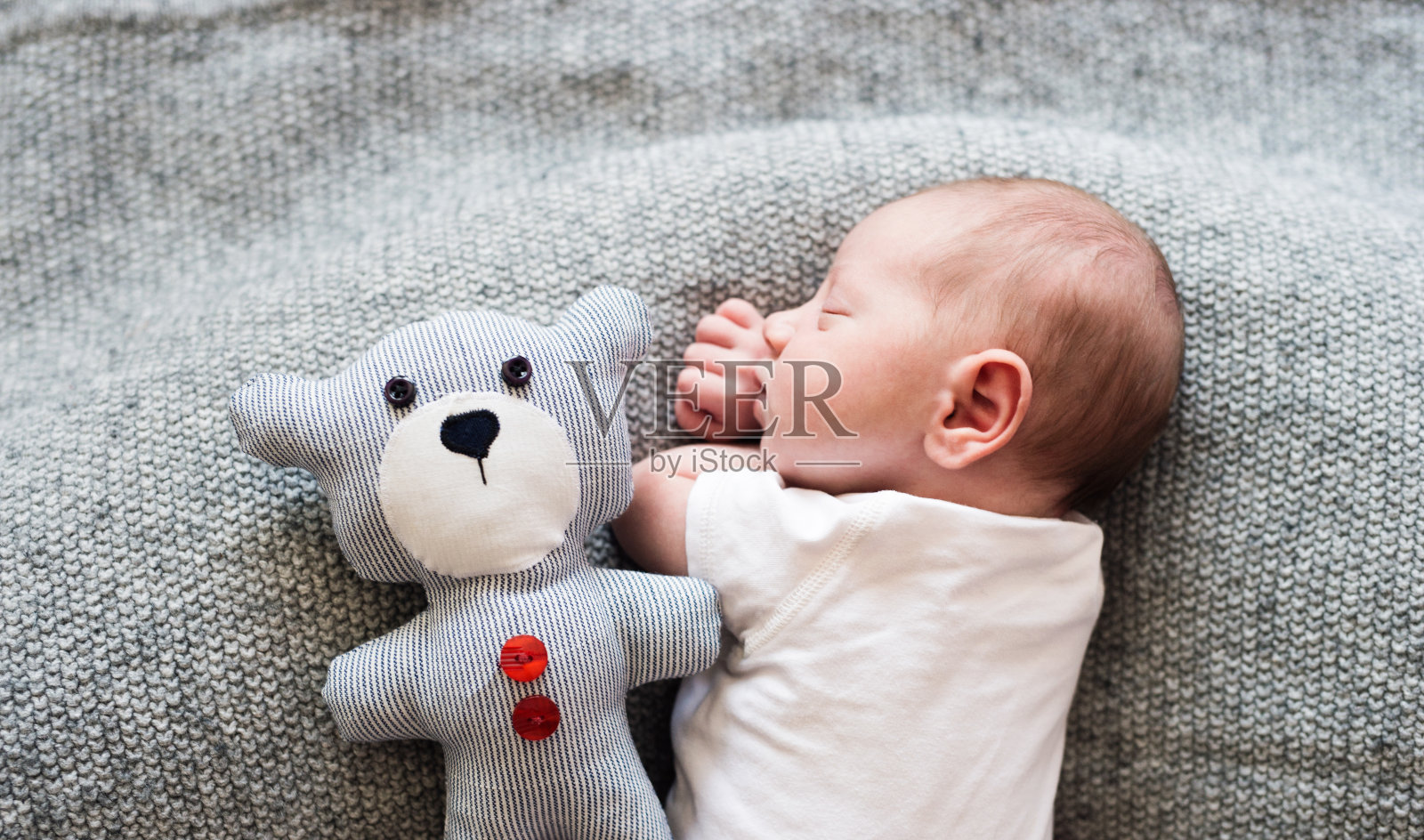 刚出生的男婴躺在床上和泰迪熊一起睡觉照片摄影图片