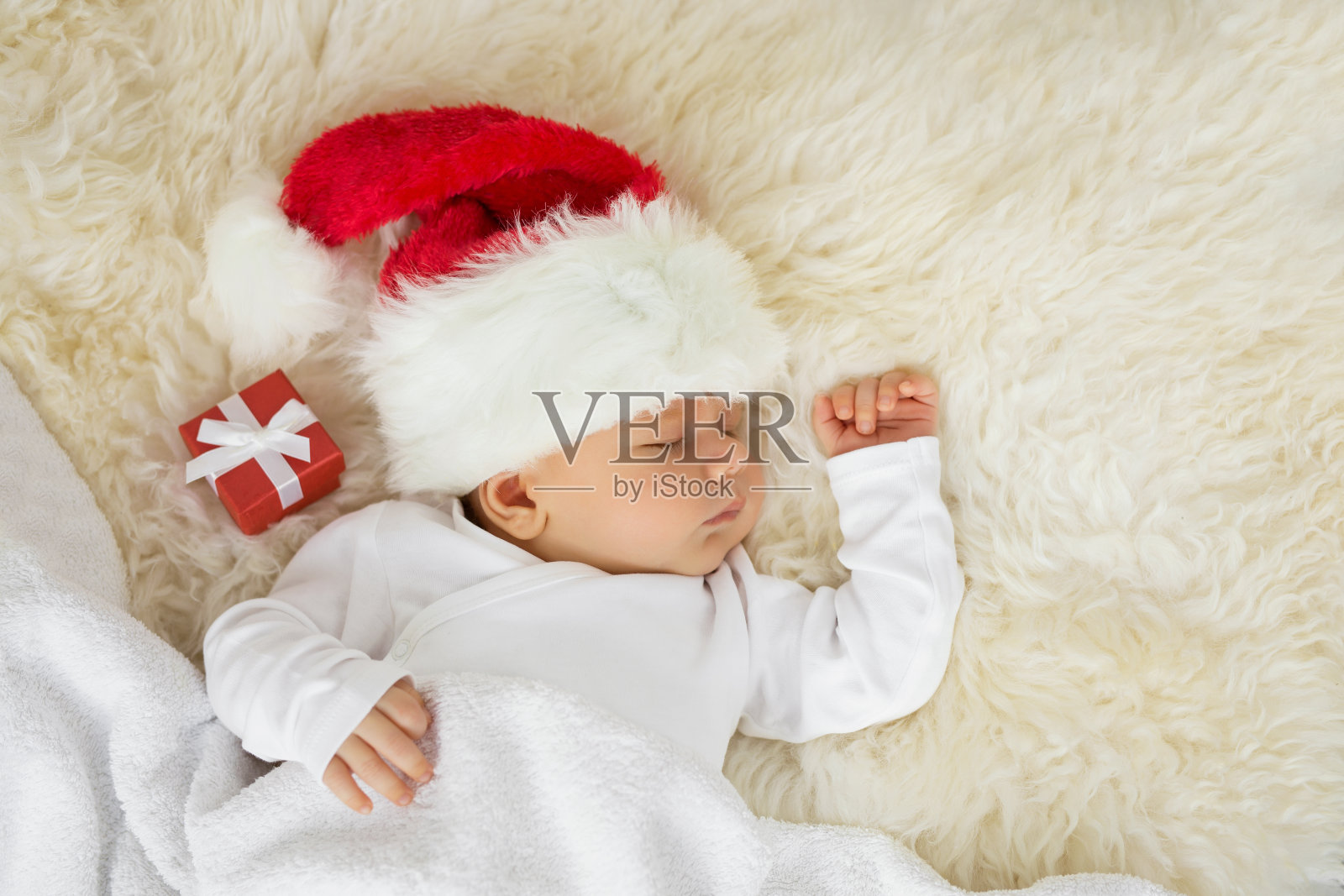 婴儿睡在圣诞帽和礼物盒照片摄影图片