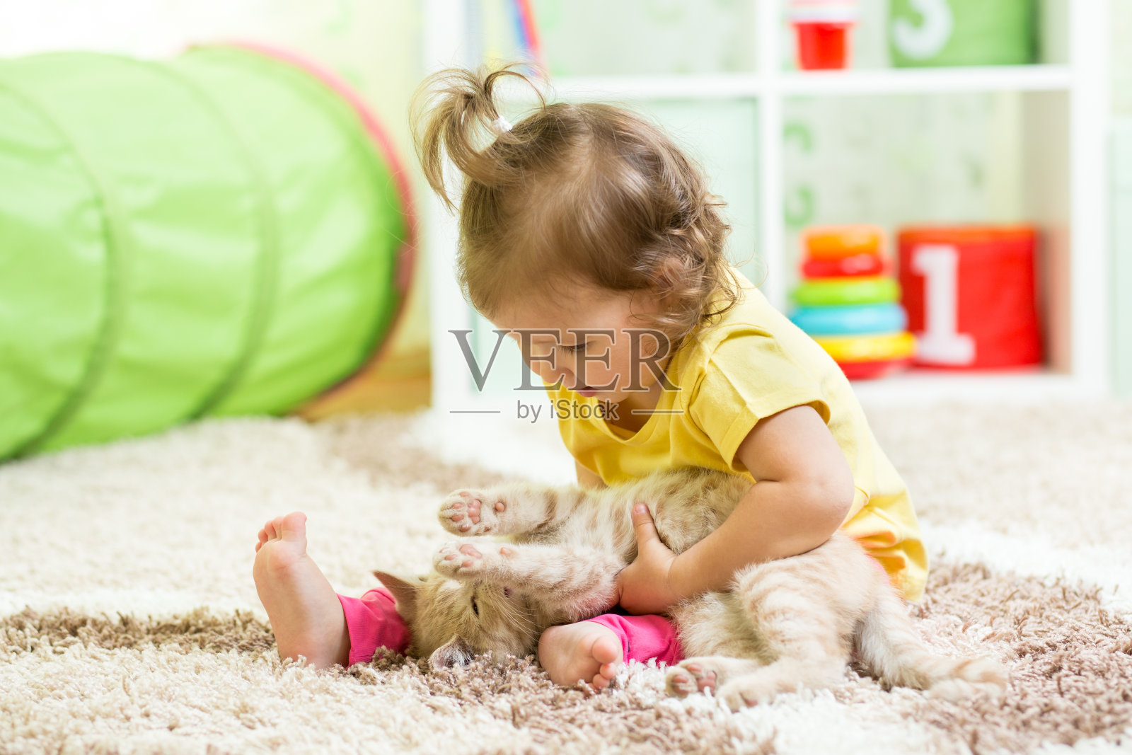 小女孩抱着她的小猫在地板上照片摄影图片