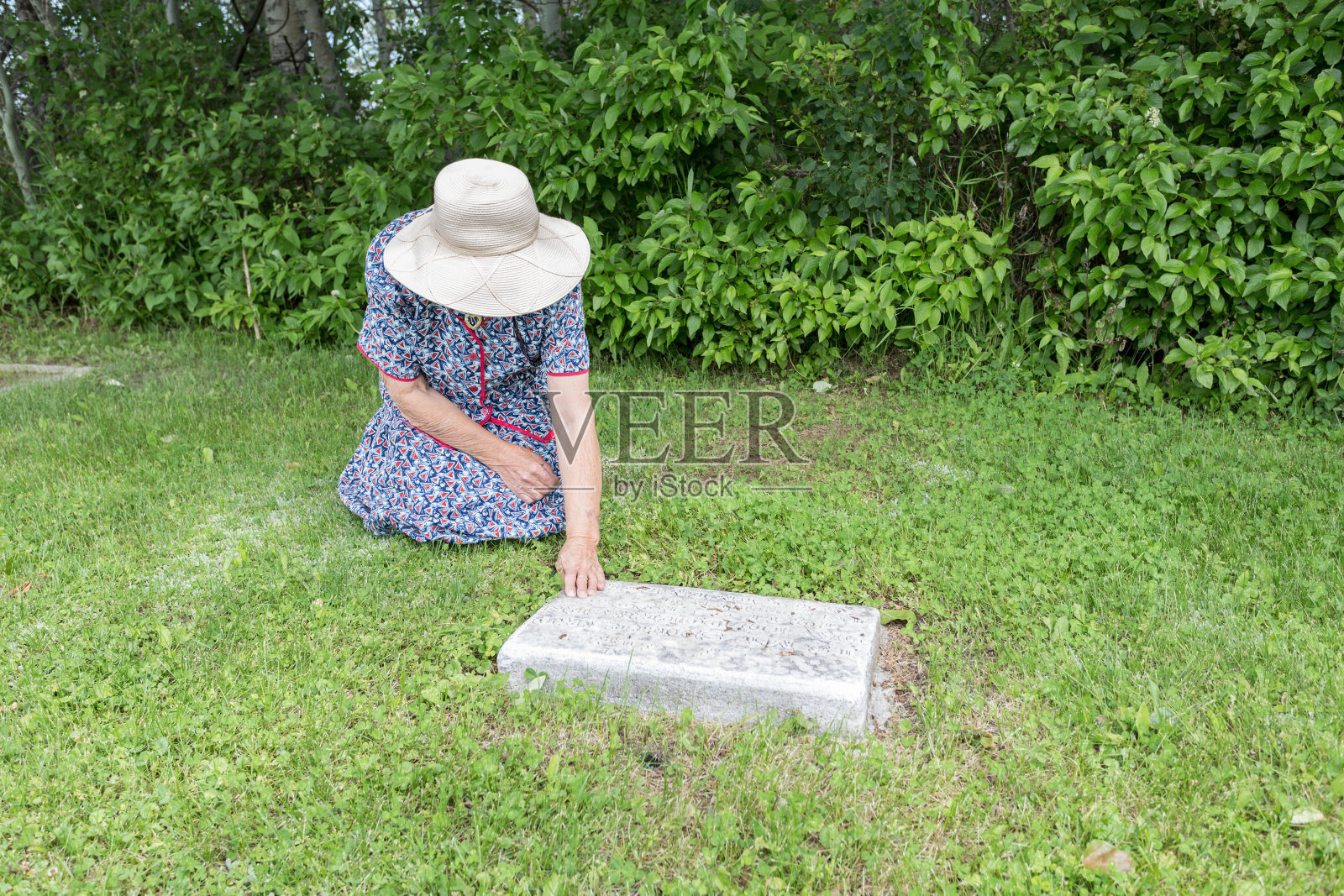 一个女人跪在坟墓旁照片摄影图片
