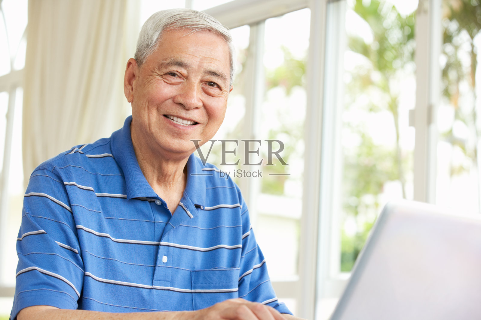 坐在书桌前使用笔记本电脑的中国老人照片摄影图片