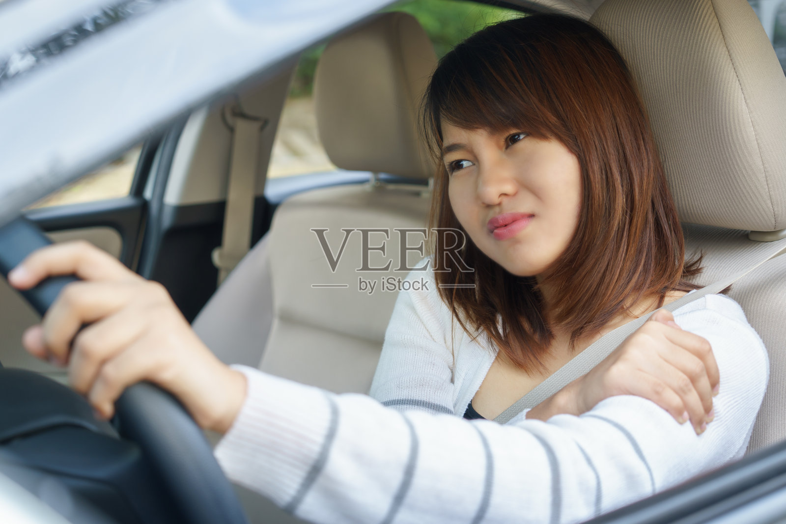 年轻女子在开车时按摩手臂或肩膀照片摄影图片