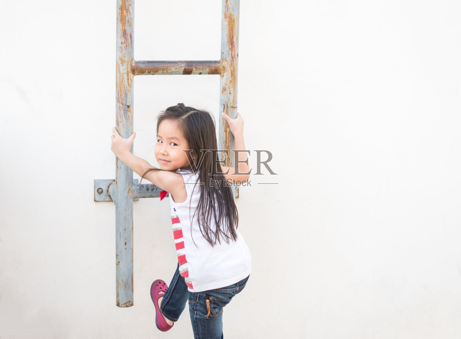 一个亚洲小女孩爬上了楼梯-消防梯照片摄影图片