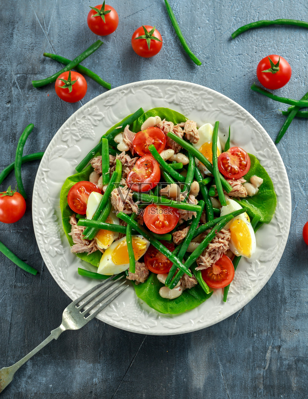 新鲜的金枪鱼青豆沙拉，鸡蛋，西红柿，豆子放在白色的盘子里。健康食品的概念照片摄影图片
