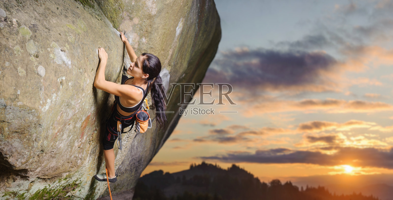 女性攀登者在大自然中用绳子攀爬巨石照片摄影图片