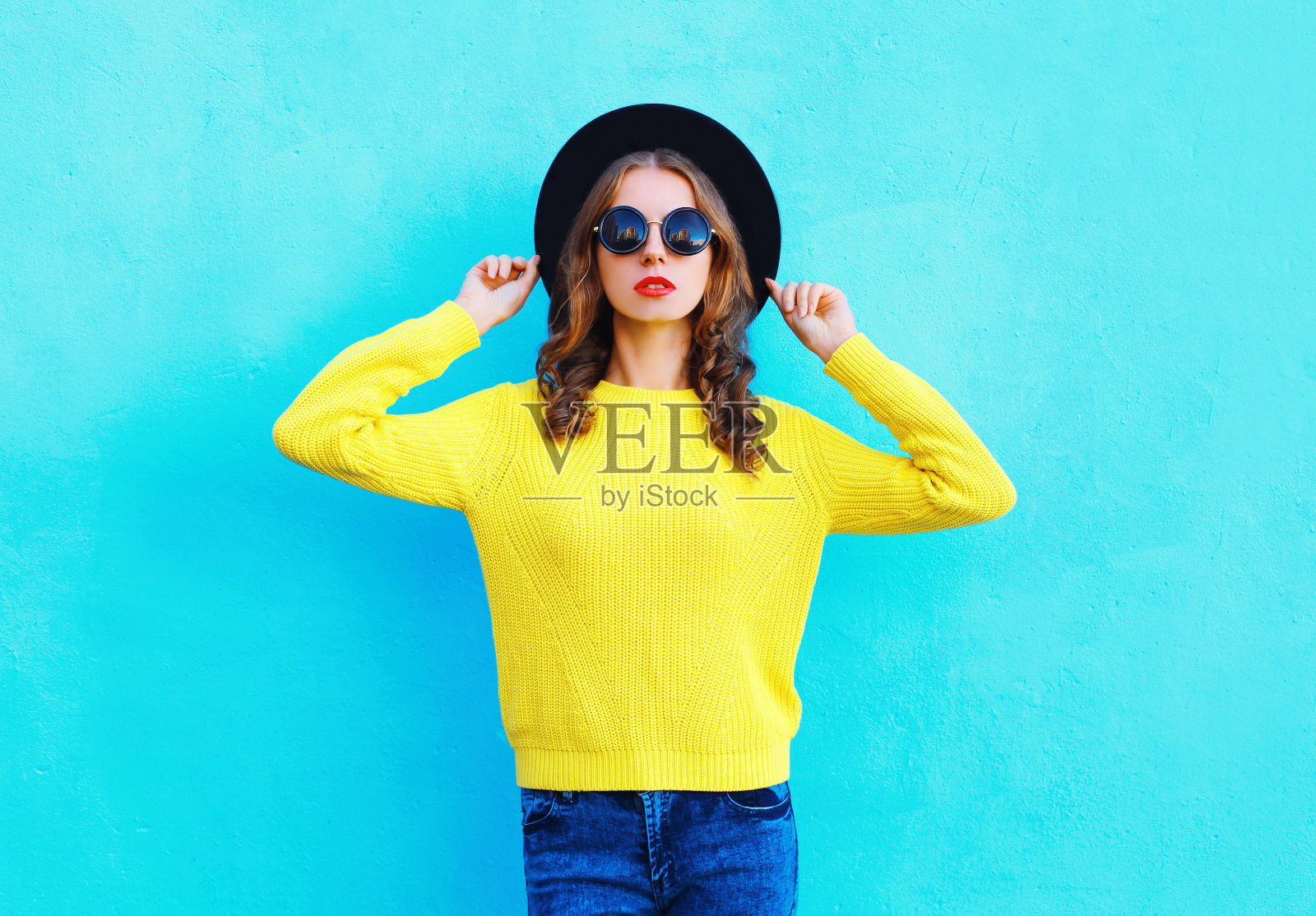 时尚的女人戴着黑色的帽子和黄色的针织毛衣照片摄影图片