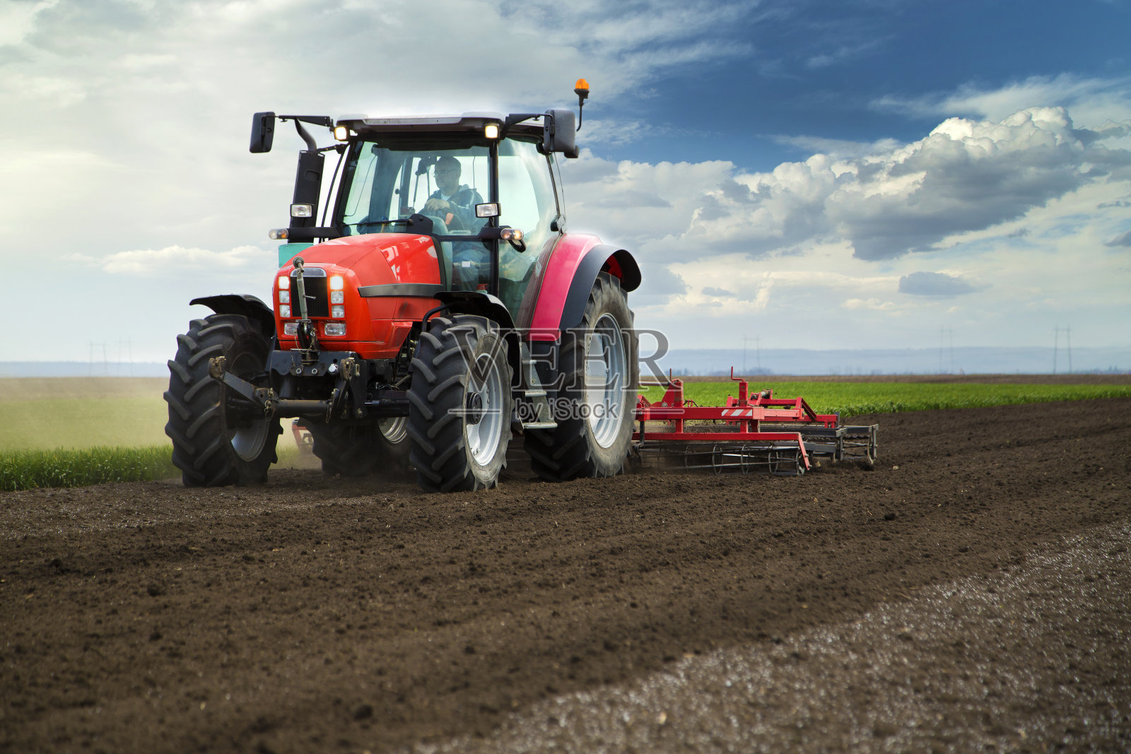 农业的特写，红色的拖拉机在蓝天上耕种田地照片摄影图片