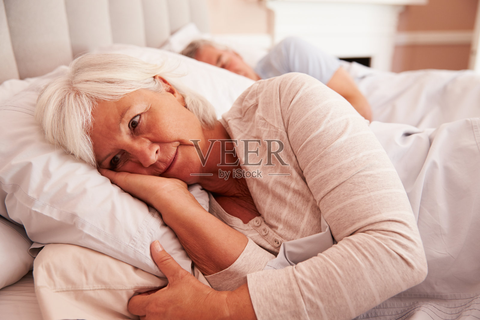 忧心忡忡的老妇人躺在床上照片摄影图片