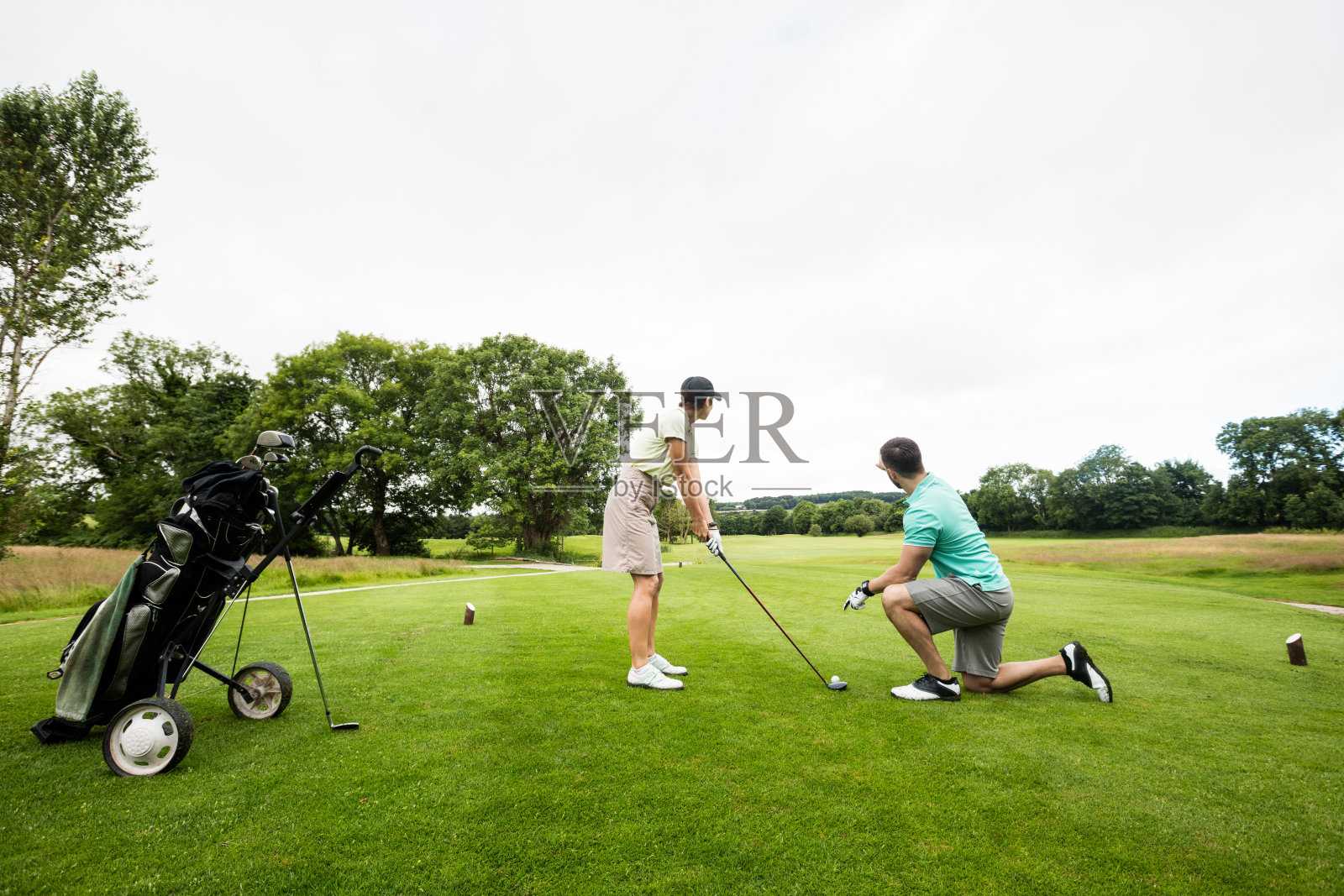 男教练协助女性学习高尔夫球照片摄影图片