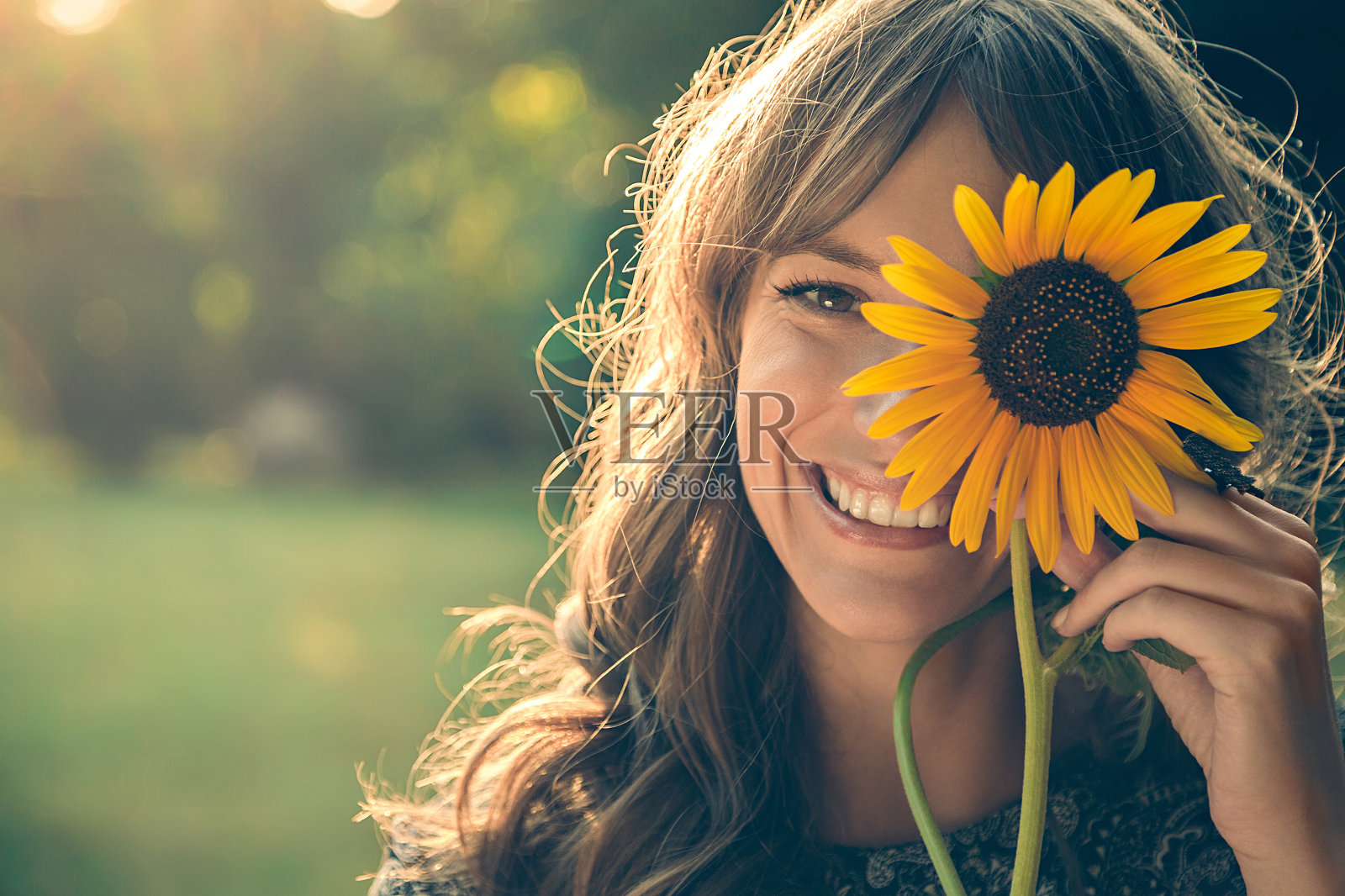 女孩在公园里用向日葵盖着脸照片摄影图片