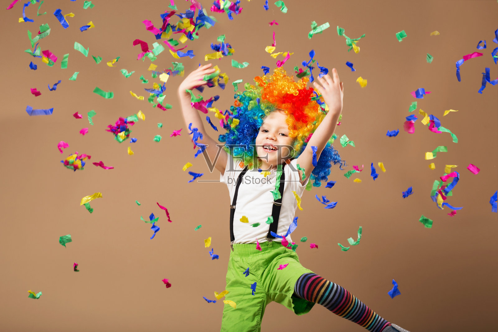 戴小丑假发的小男孩跳得很开心照片摄影图片
