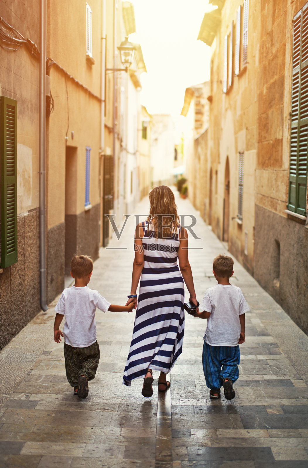 母亲带着两个儿子参观地中海小镇。照片摄影图片