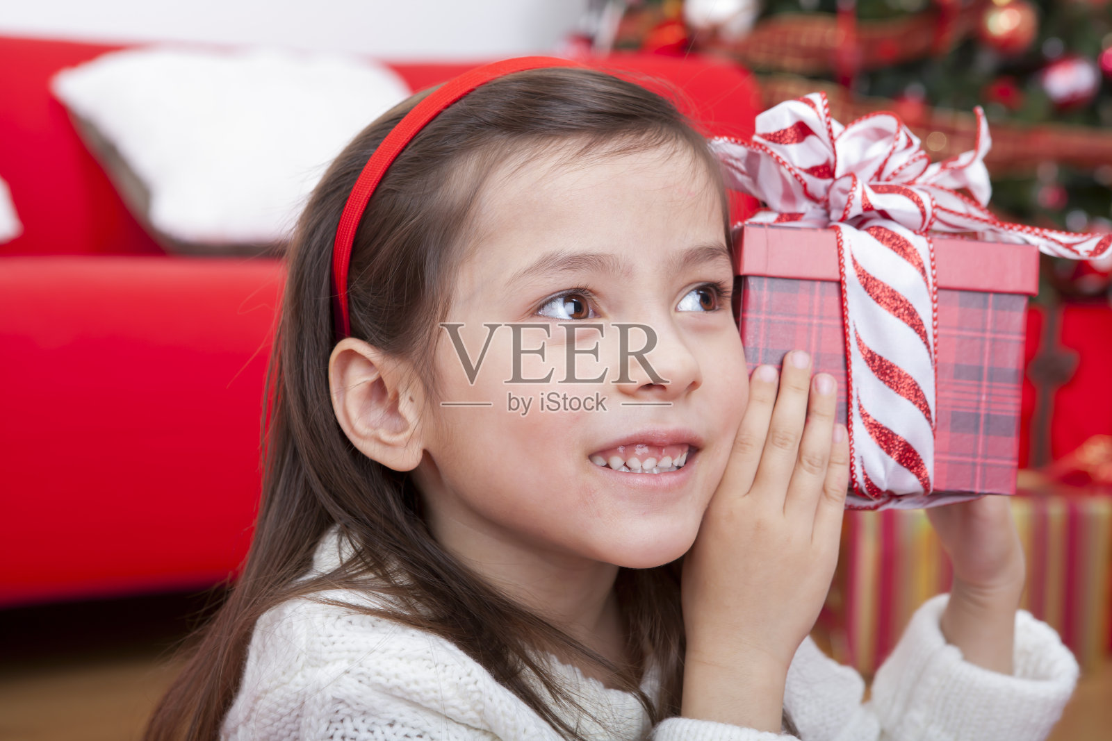 快乐的女孩听着她的圣诞礼物照片摄影图片