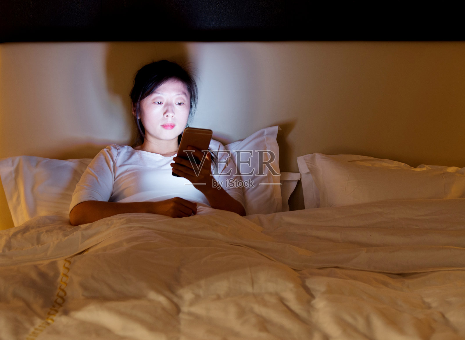 女人在床上玩智能手机照片摄影图片
