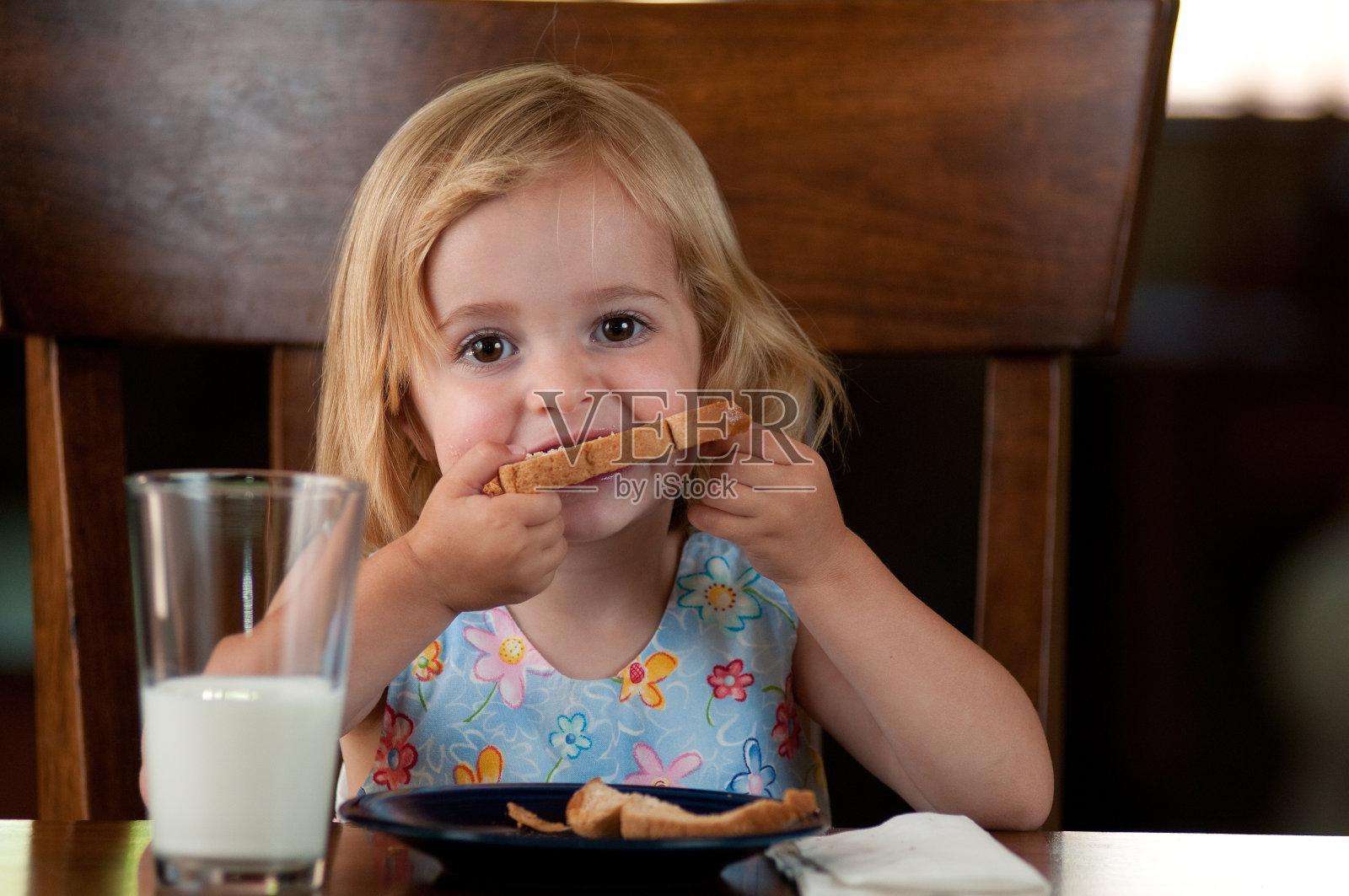 小女孩在吃烤面包。照片摄影图片