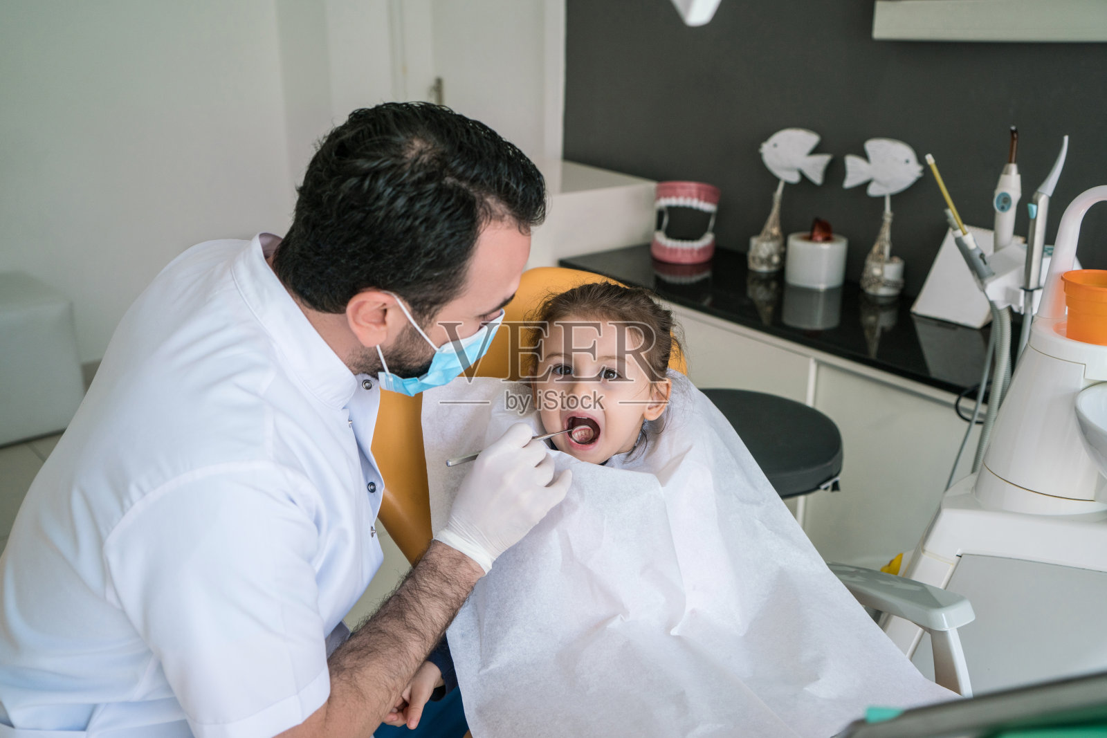 快乐的蹒跚学步的小女孩正在牙医诊所检查牙齿。照片摄影图片