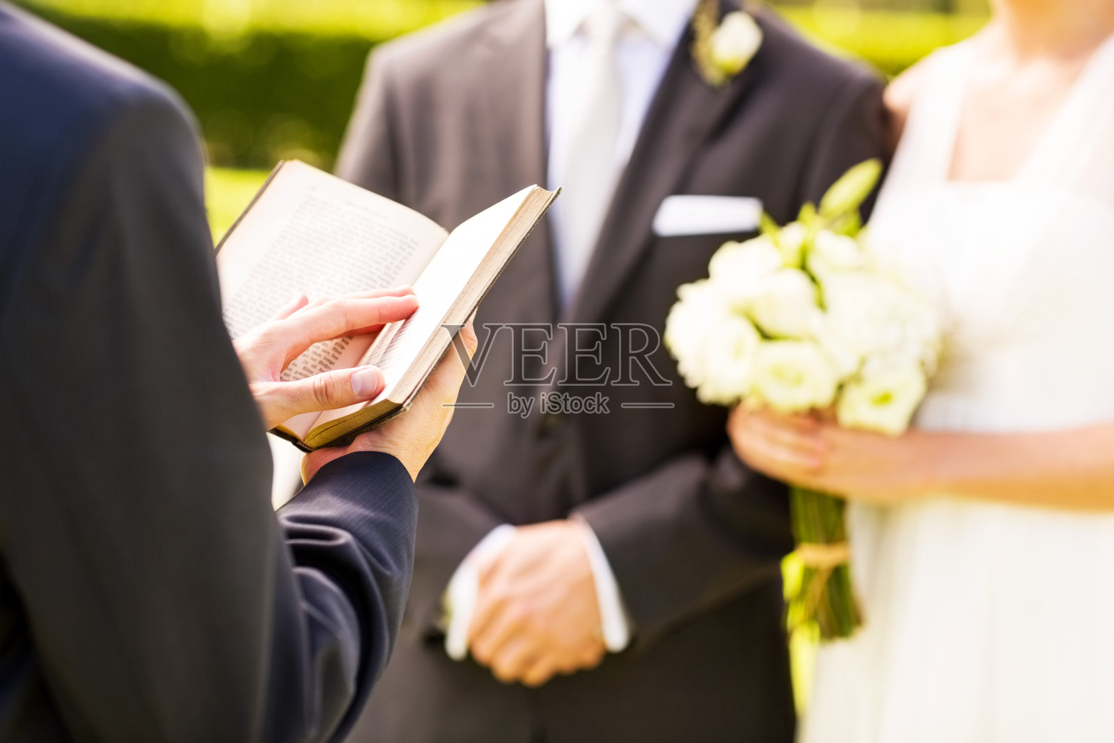 牧师和新郎新娘在户外婚礼上拿着圣经照片摄影图片