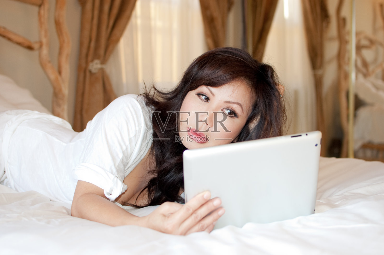 一位亚洲妇女拿着药片躺在床上照片摄影图片