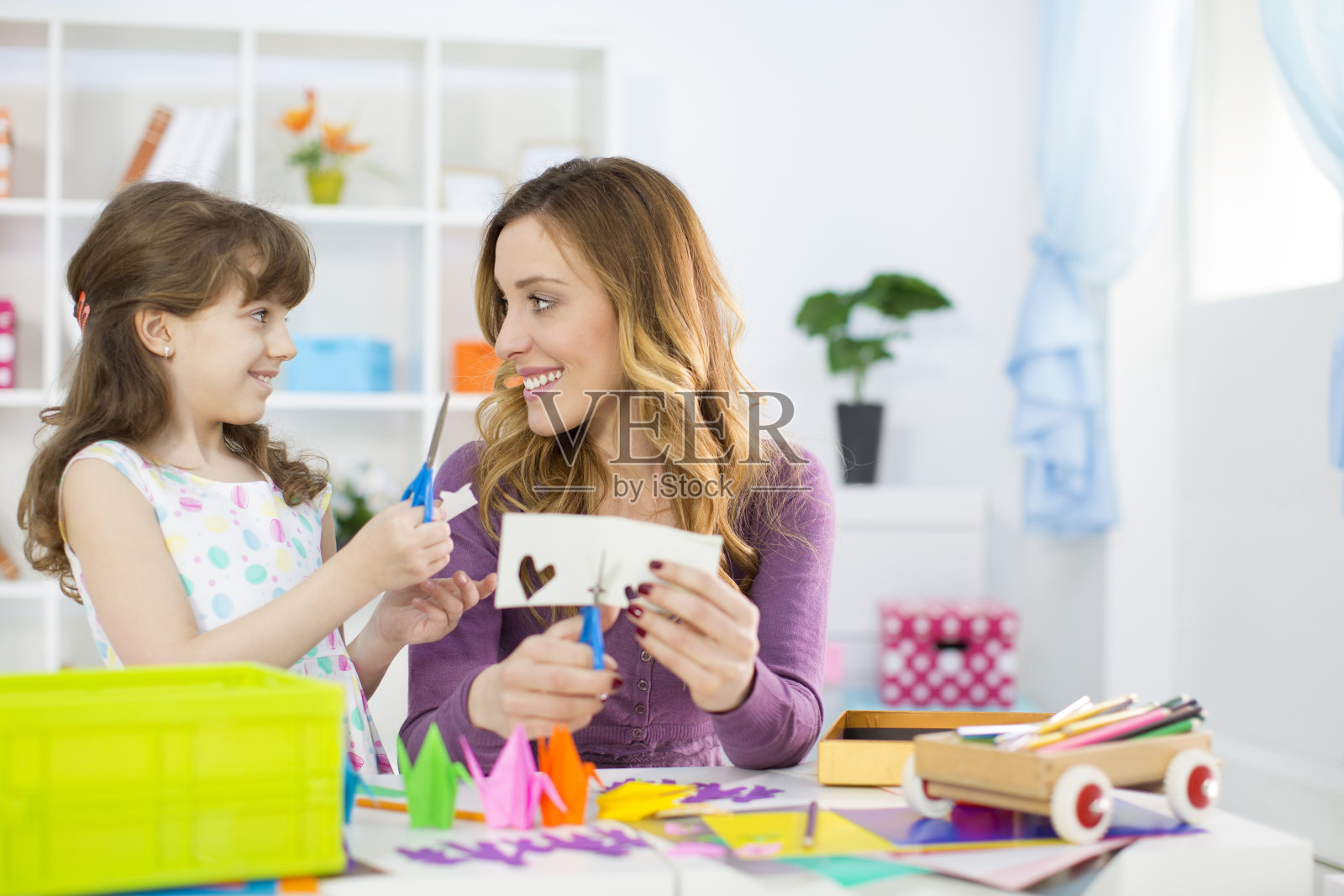 母亲和女儿在做折纸。照片摄影图片