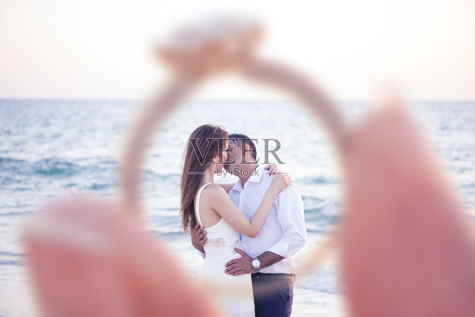 订婚的情侣在海上接吻。照片摄影图片