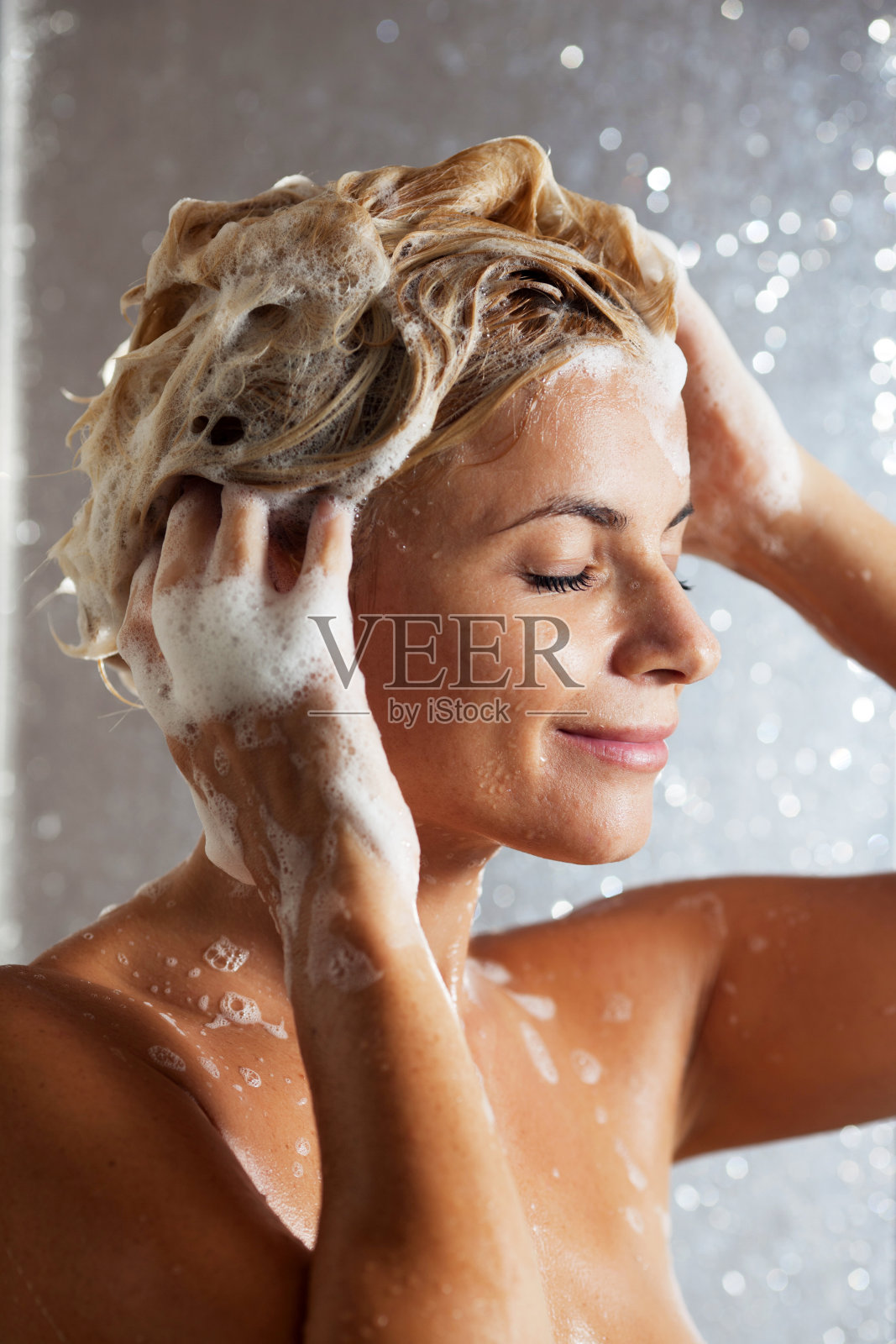 近距离的女人洗她的头发在淋浴。照片摄影图片