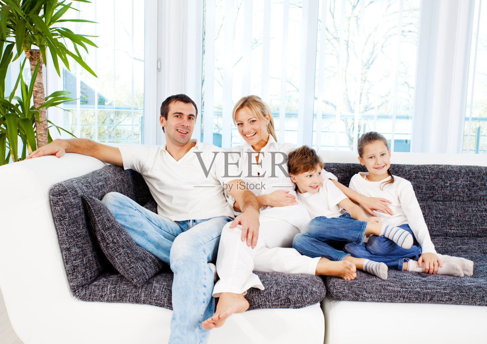 一家人微笑着坐在沙发上，享受生活。照片摄影图片