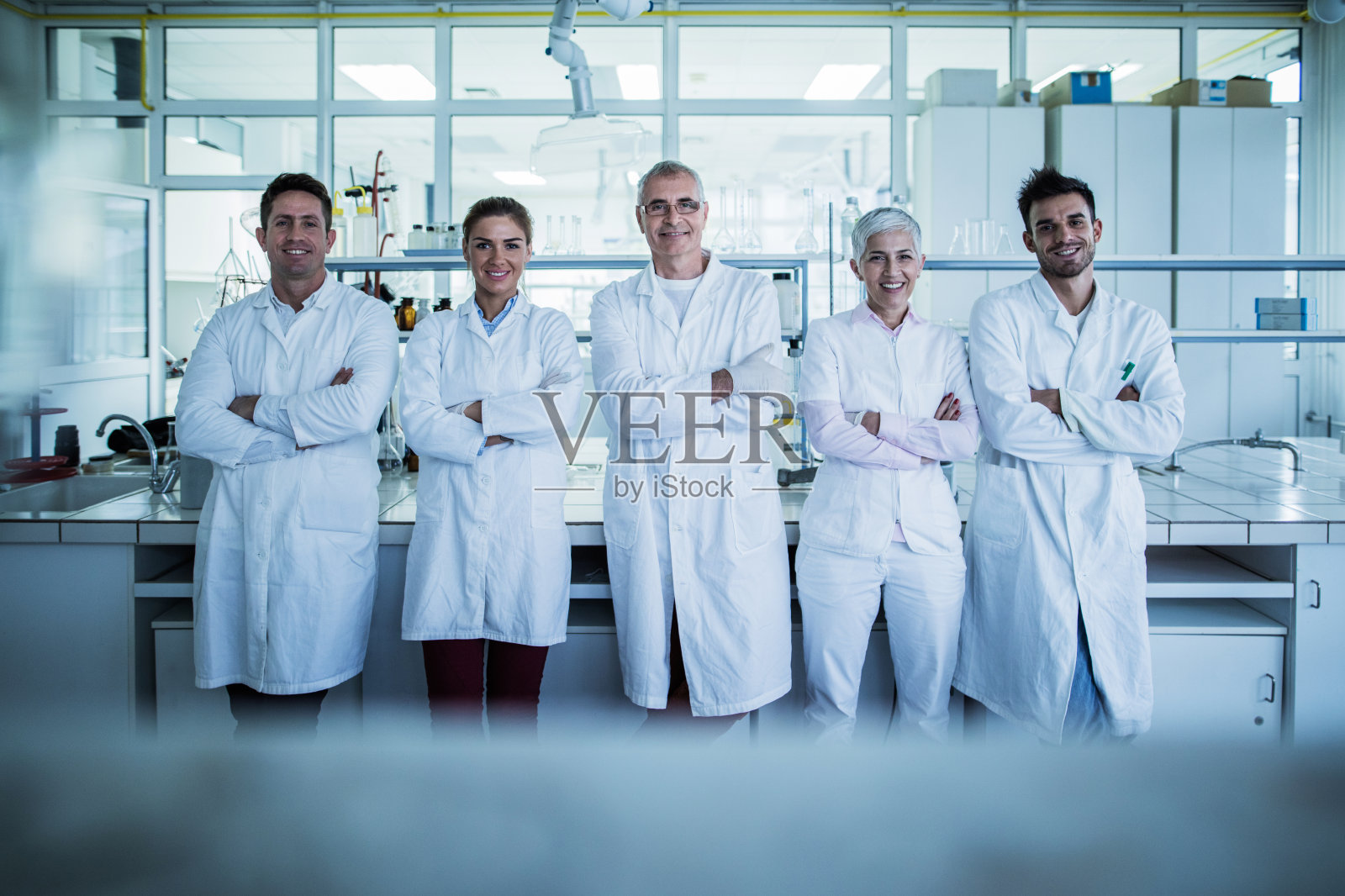 实验室里一群抱着双臂的快乐科学家。照片摄影图片
