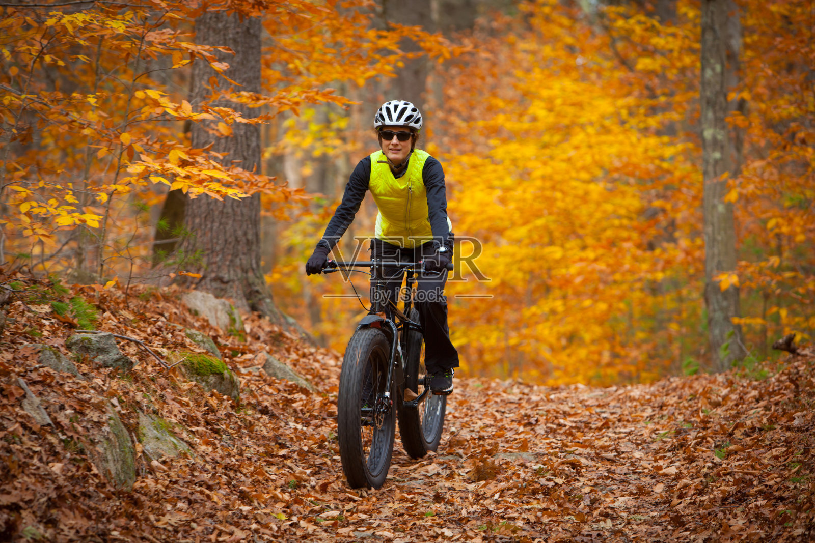 有魅力的女人骑着一辆肥自行车在树叶覆盖的小径上照片摄影图片