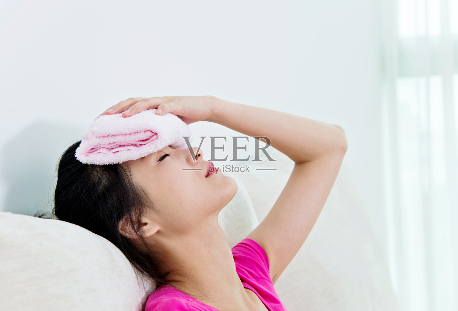 一个头疼的年轻亚洲女人坐在沙发上照片摄影图片
