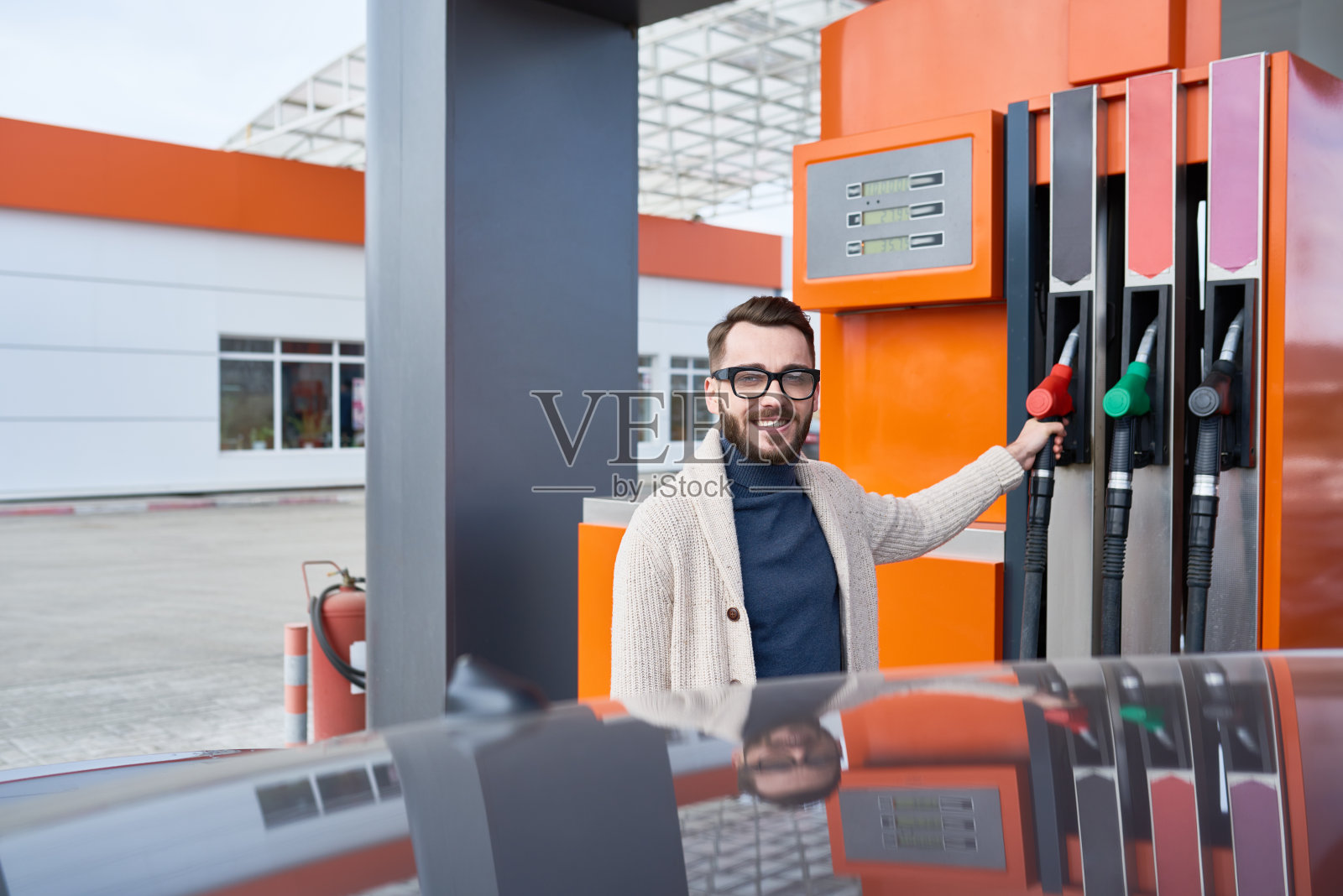 微笑的现代人在加油站用油泵照片摄影图片
