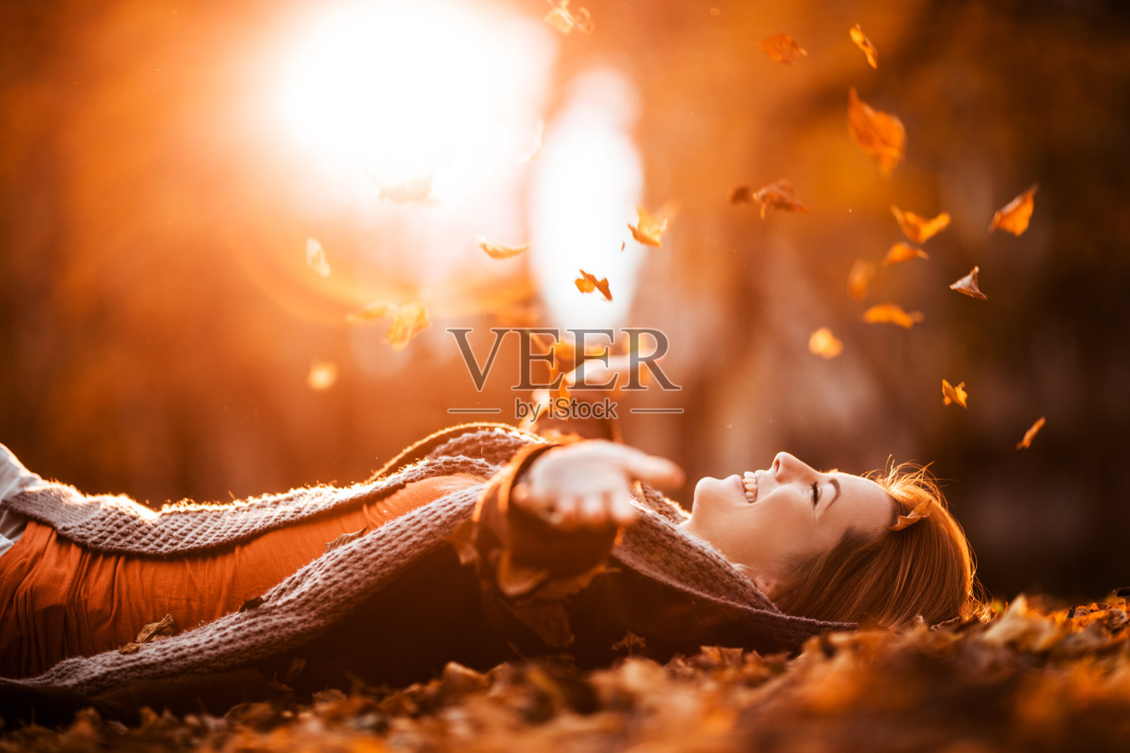 无忧无虑的女人，在大自然中悠闲地抛下秋叶。照片摄影图片
