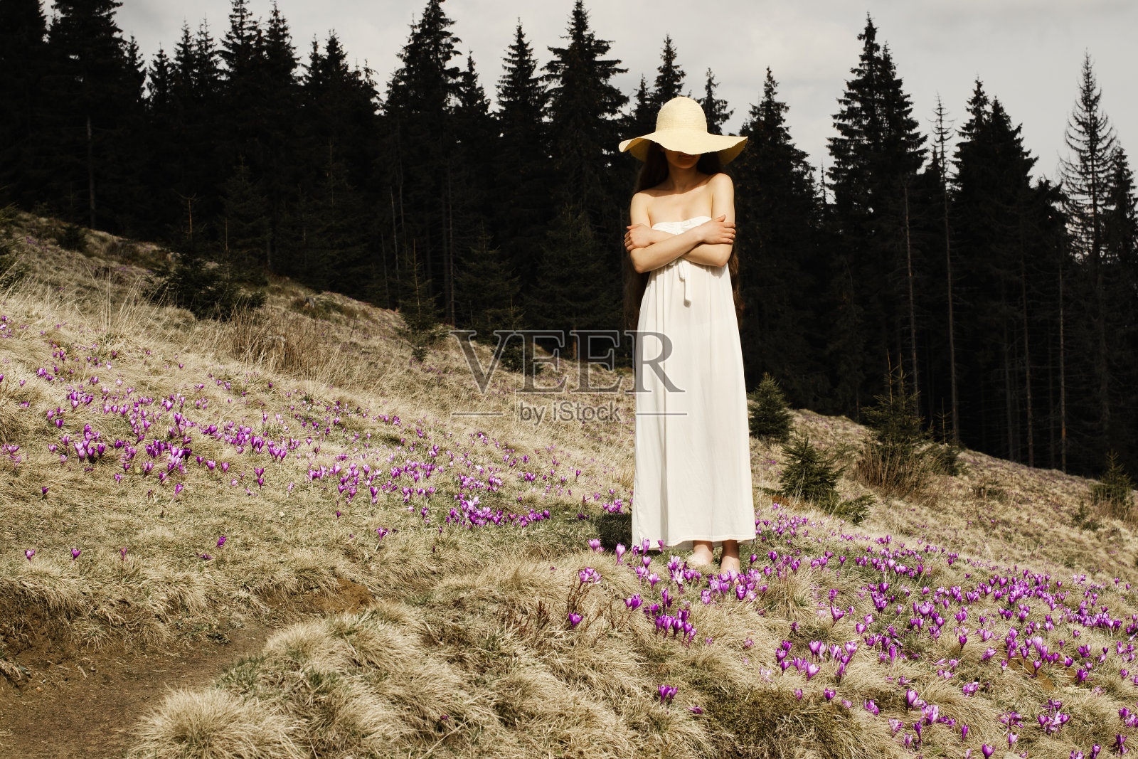 年轻女子站在山中鲜花盛开的山坡上照片摄影图片