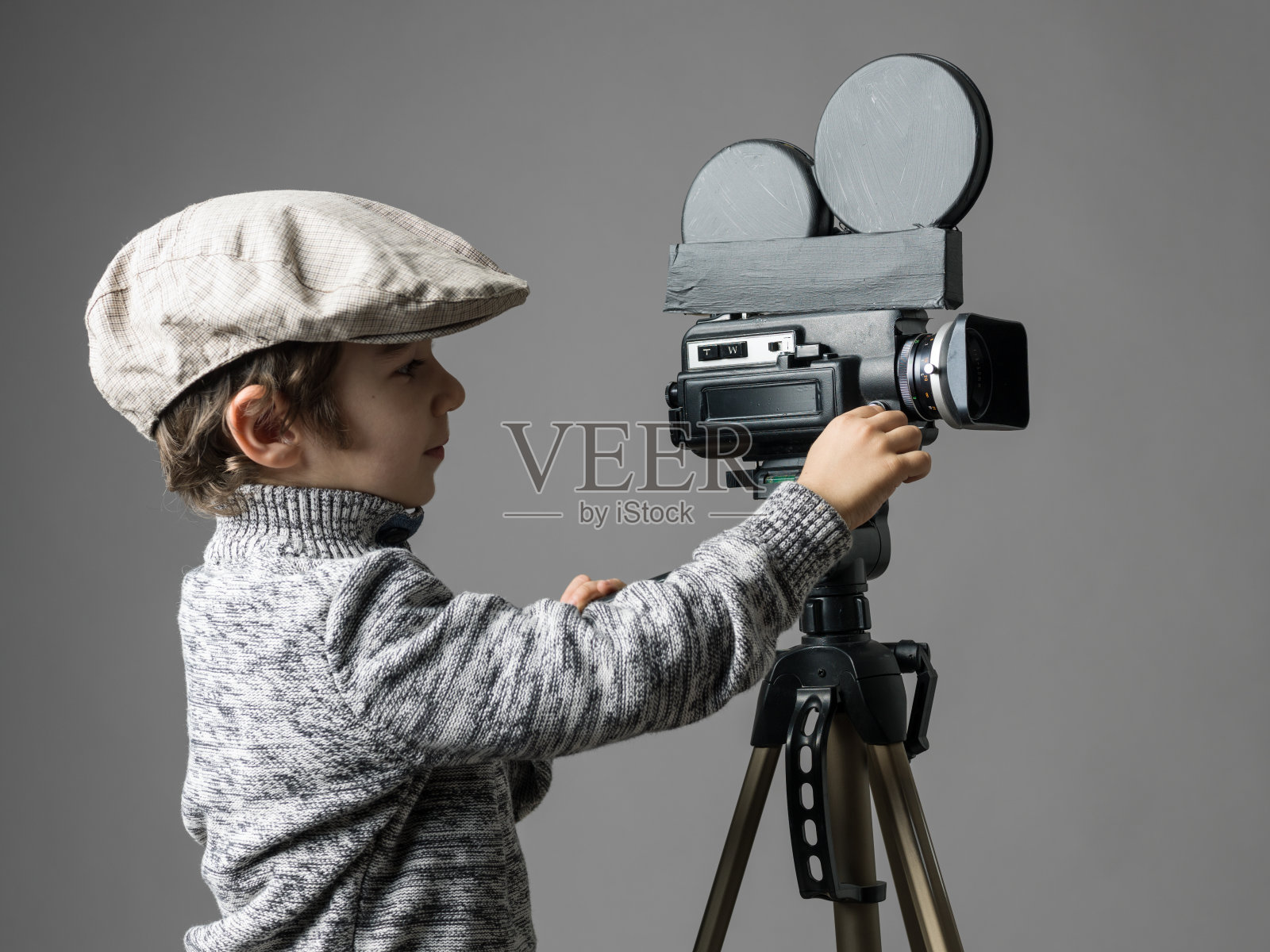 小男孩戴着平顶帽，用家用改装摄像机摆姿势照片摄影图片