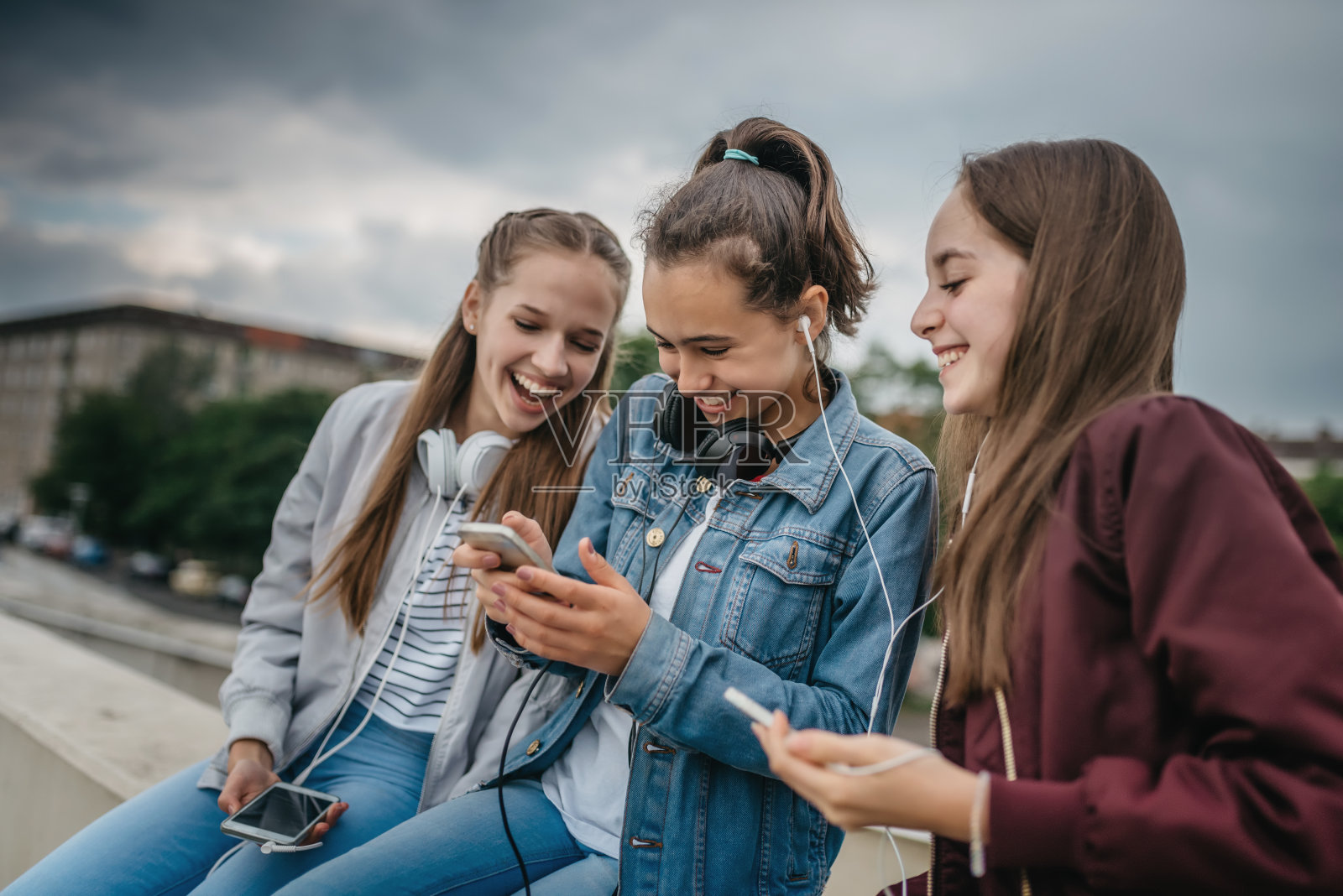 三个十几岁的女孩在户外玩智能手机照片摄影图片