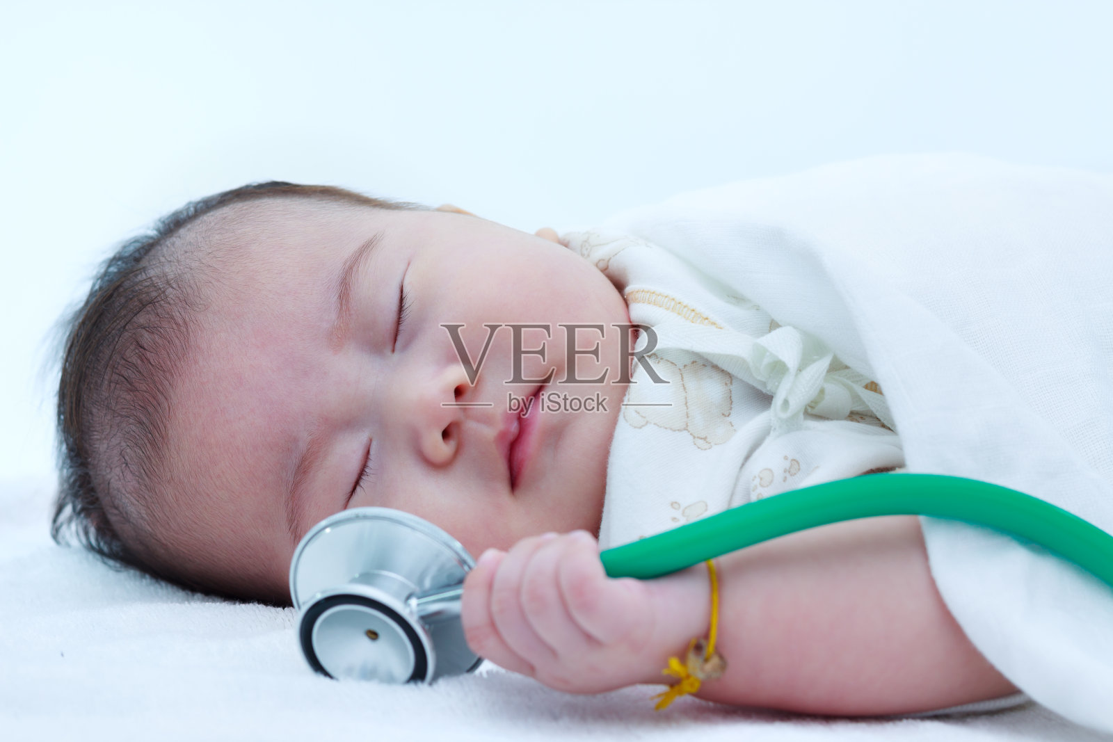 一个美丽的睡觉的婴儿与听诊器的特写肖像。照片摄影图片