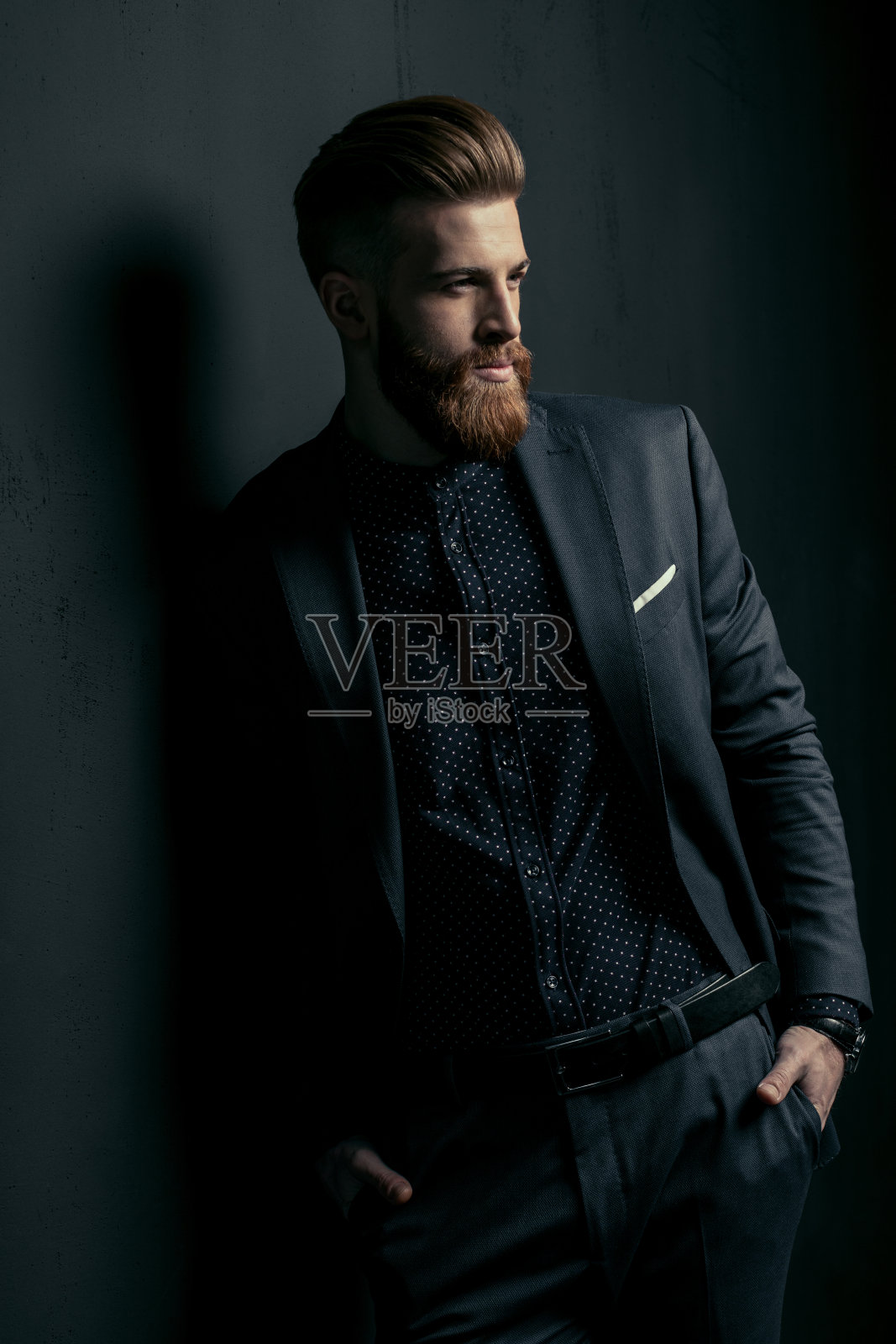 时髦英俊的胡子男子站在时尚的西装与手在口袋在黑色照片摄影图片