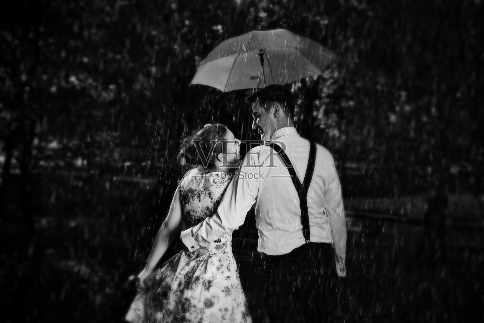 年轻浪漫的情侣在雨中调情。黑色和白色照片摄影图片