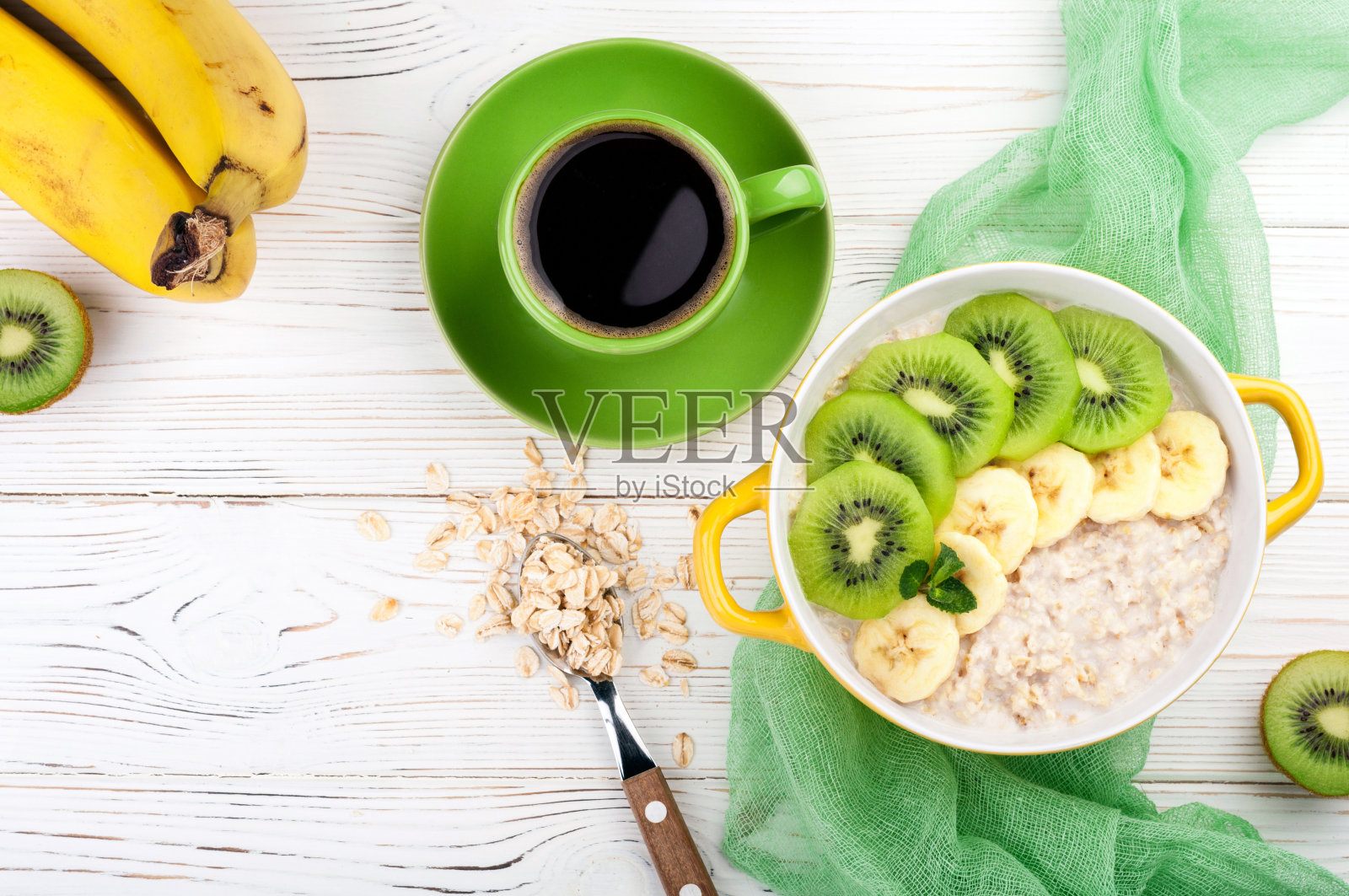 早餐有燕麦粥，咖啡杯和水果。猕猴桃和香蕉燕麦片。健康的早餐概念。俯视图照片摄影图片