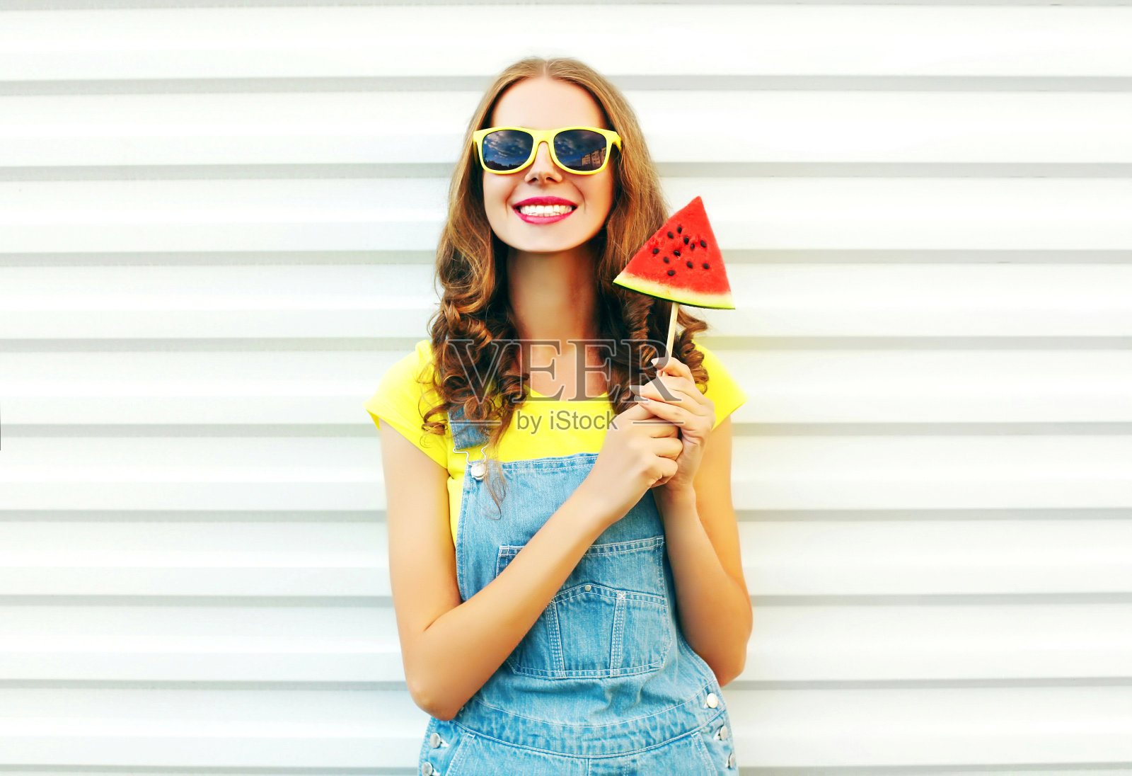 一个快乐的微笑的女人，在白色的背景上有一片西瓜冰淇淋照片摄影图片
