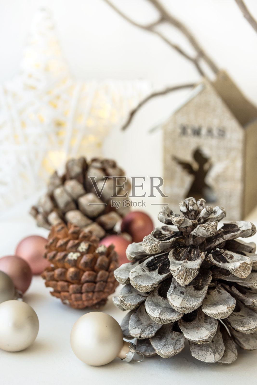 白色圣诞装饰构图，大松果，散落的小饰品，闪亮的星星，木制烛台，干枯的树枝背景，极简主义照片摄影图片