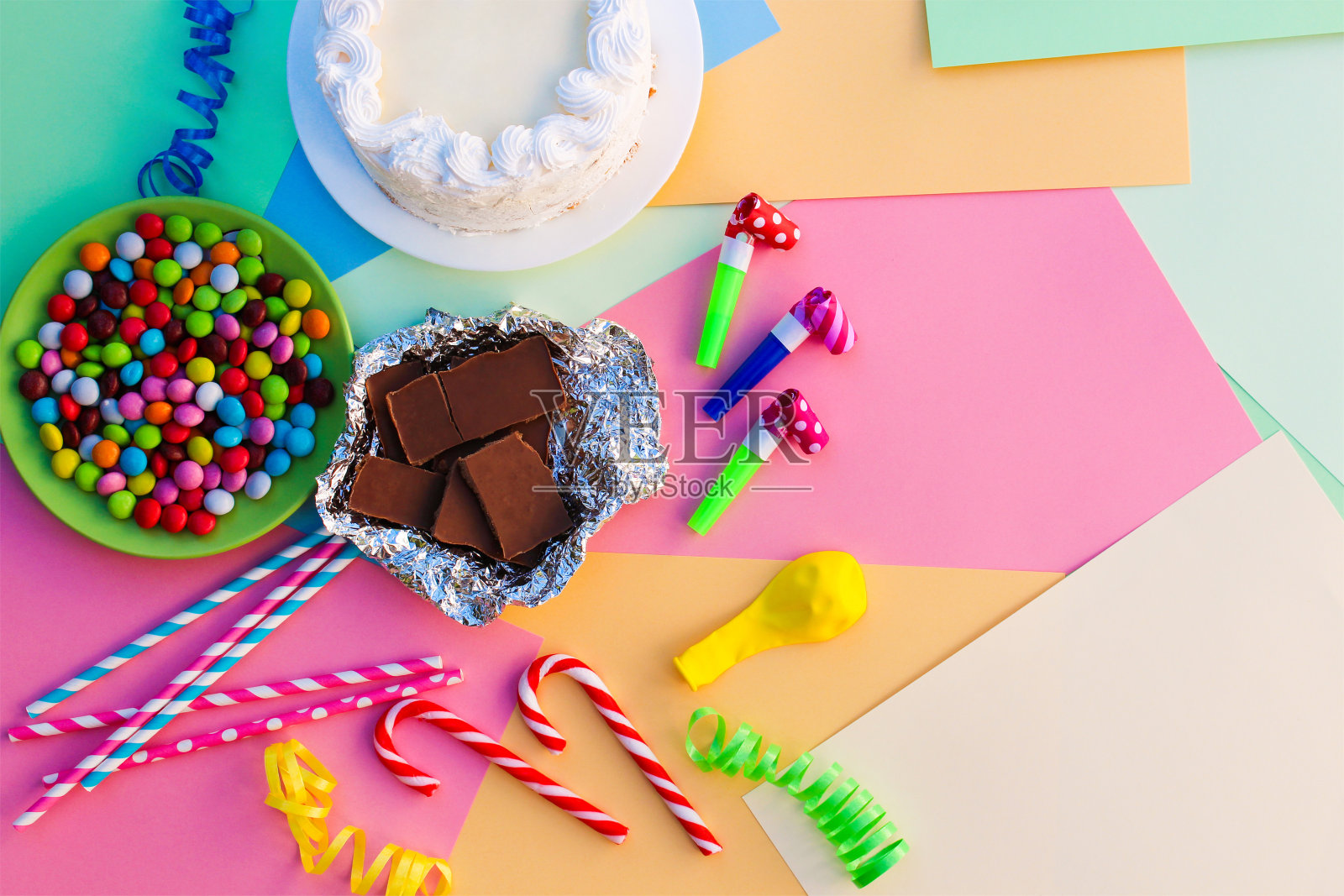 蛋糕，糖果，巧克力，口哨，彩带，节日桌上的气球。儿童生日聚会的概念。照片摄影图片