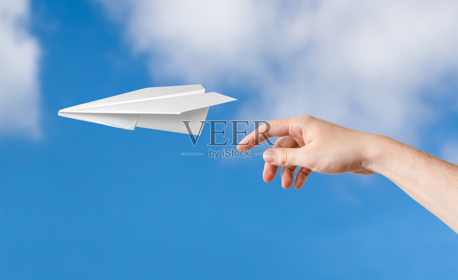 手扔的是折纸飞机。背景是蓝色的天空。照片摄影图片