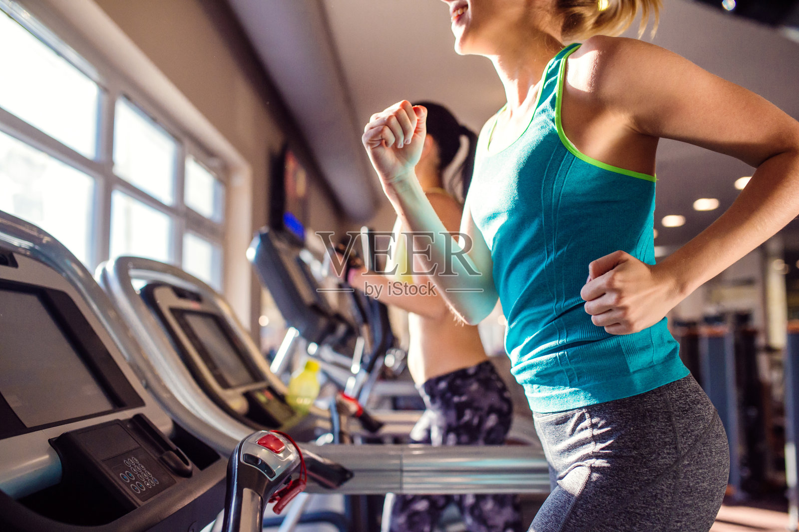 两个健康的女人在现代健身房的跑步机上跑步照片摄影图片