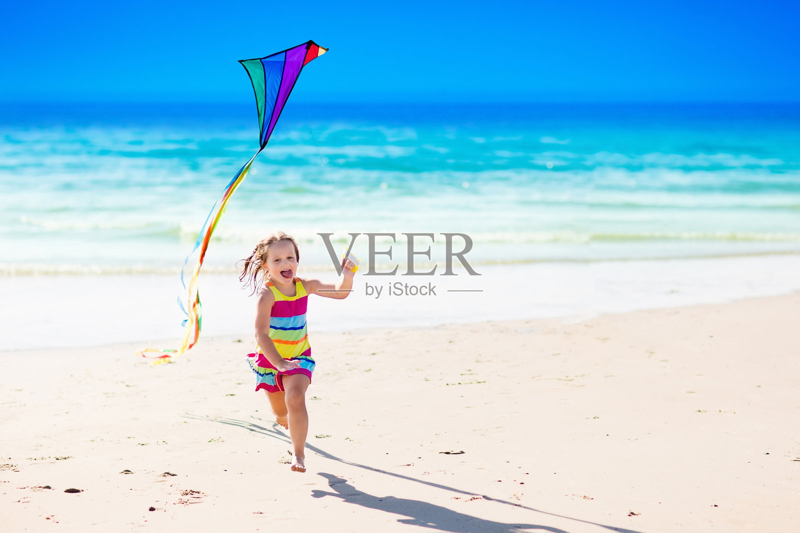 孩子在热带海滩上放风筝照片摄影图片